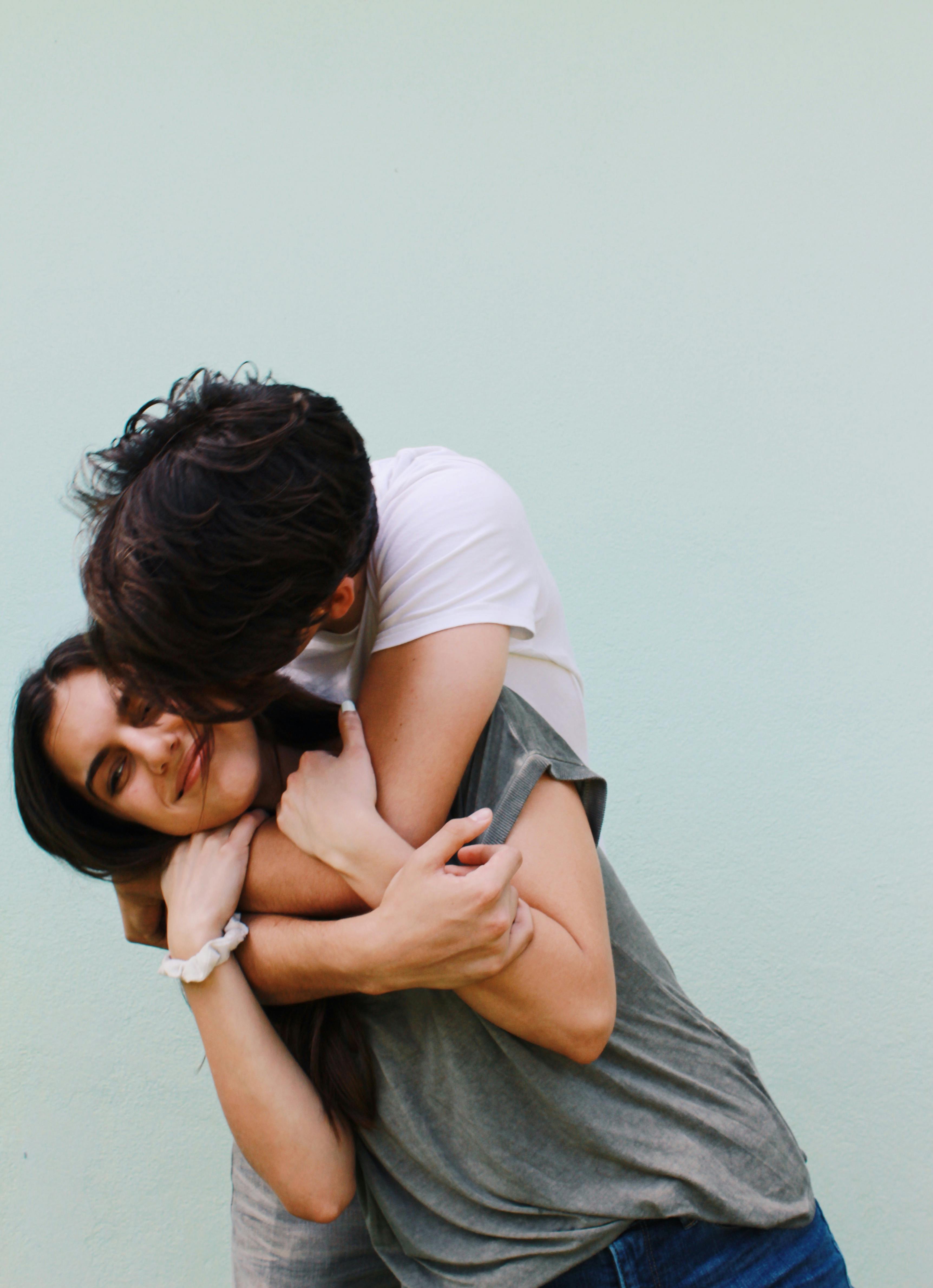 Un hombre besando y abrazando a una mujer de aspecto contrariado | Fuente: Pexels