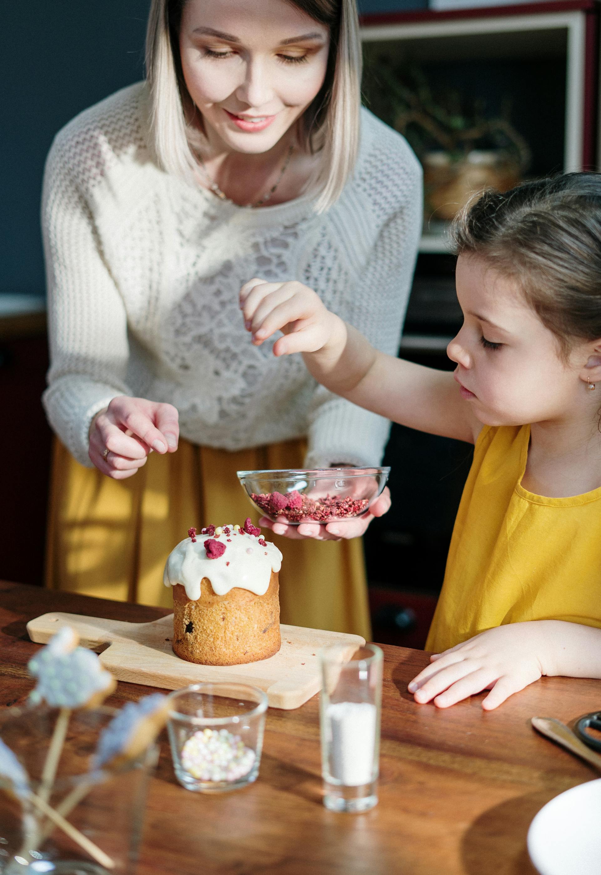 Una mujer y una niña decorando un pastel | Foto: Pexels