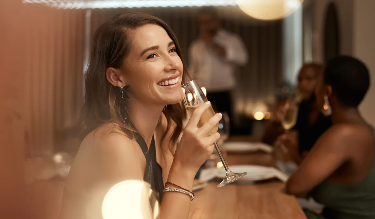 Una mujer con una copa de champán en un restaurante | Foto: Shutterstock