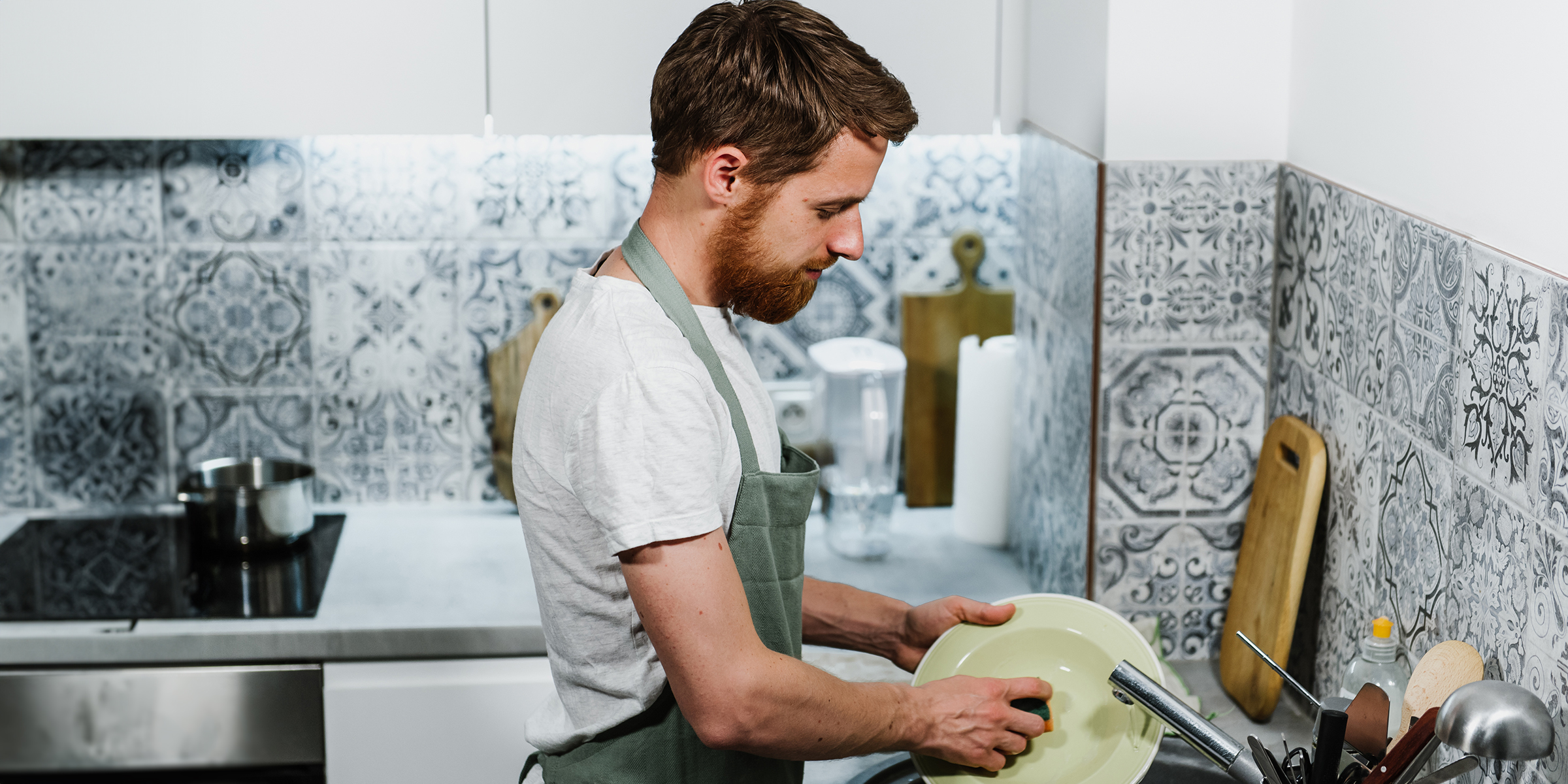 Un hombre lava los platos en la cocina | Fuente: Shutterstock