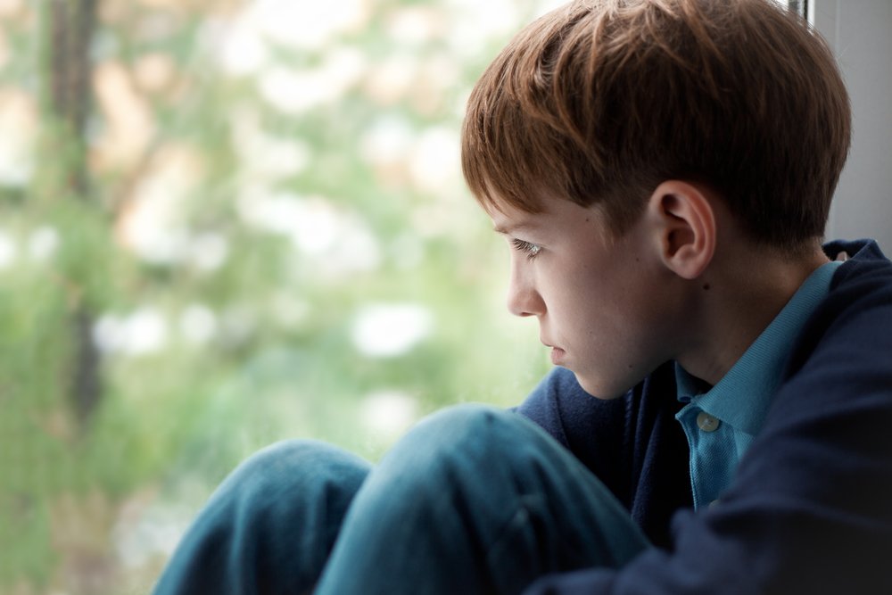 Niño enojado sentado junto a una ventana. | Foto: Shutterstock