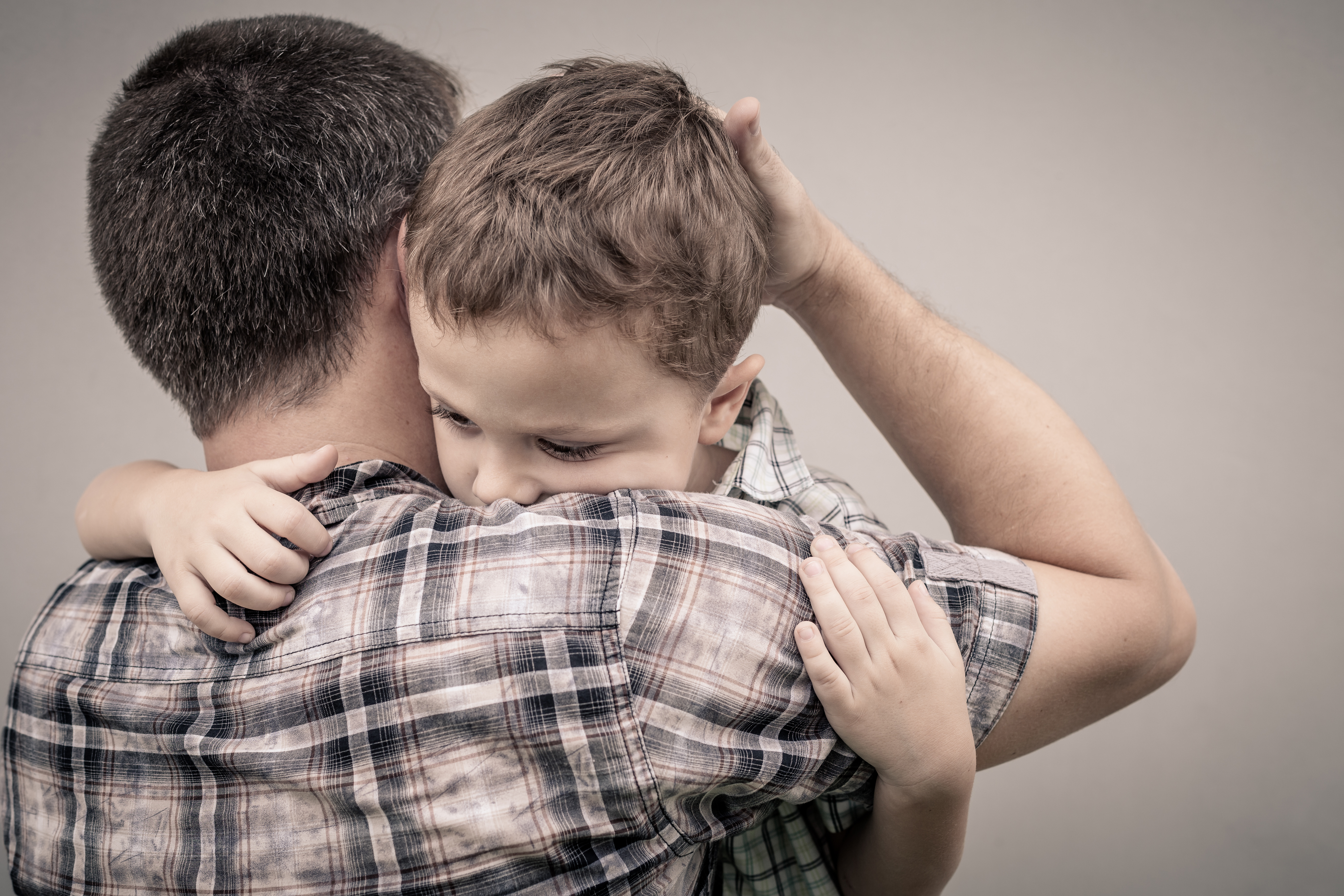 Un padre abrazando a su hijo de aspecto triste. | Foto: Shutterstock