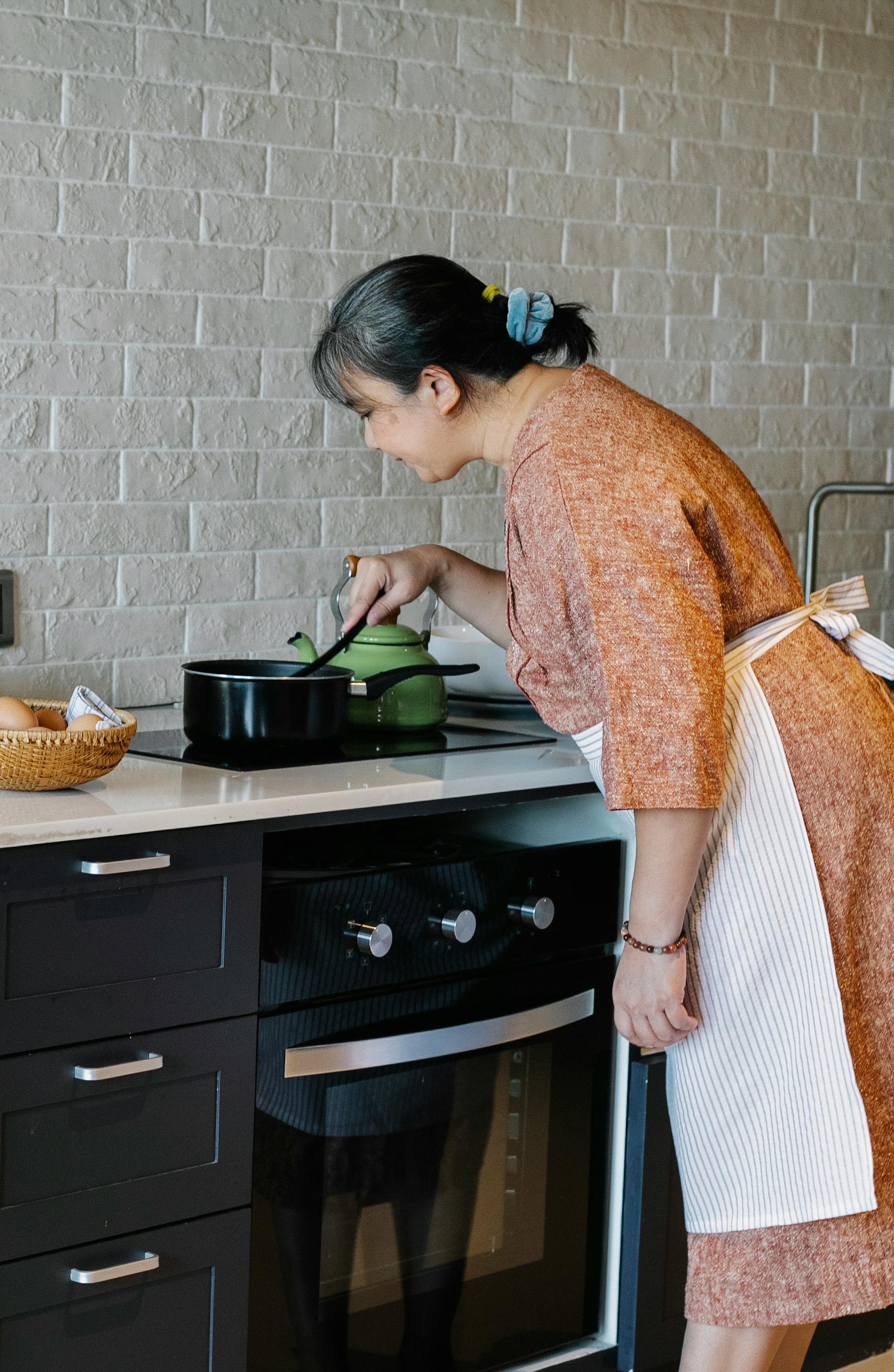 Una mujer mayor removiendo una olla en la cocina | Fuente: Pexels