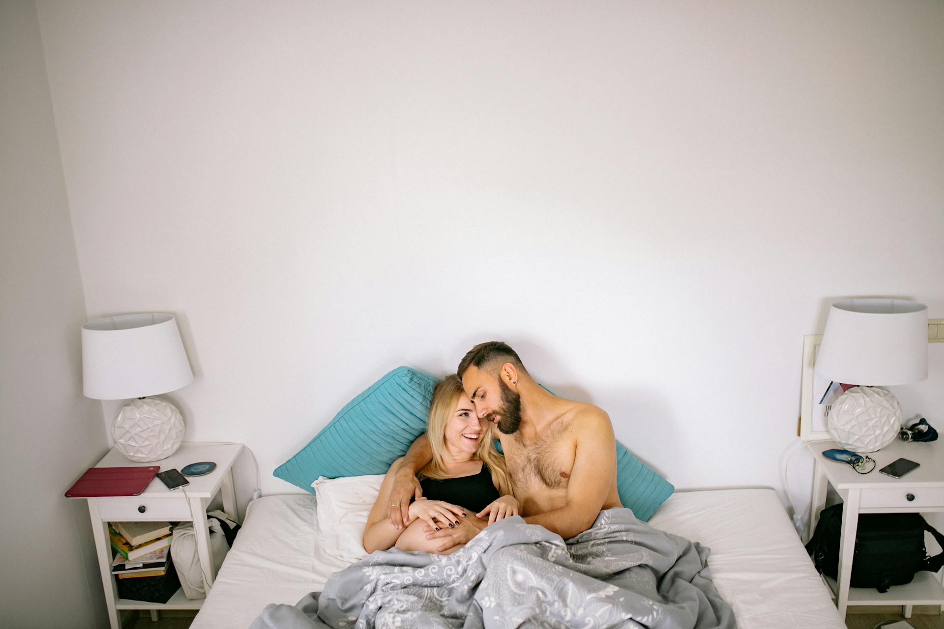 Un marido tocando la barriga de su mujer embarazada mientras se acurrucan en la cama | Fuente: Pexels