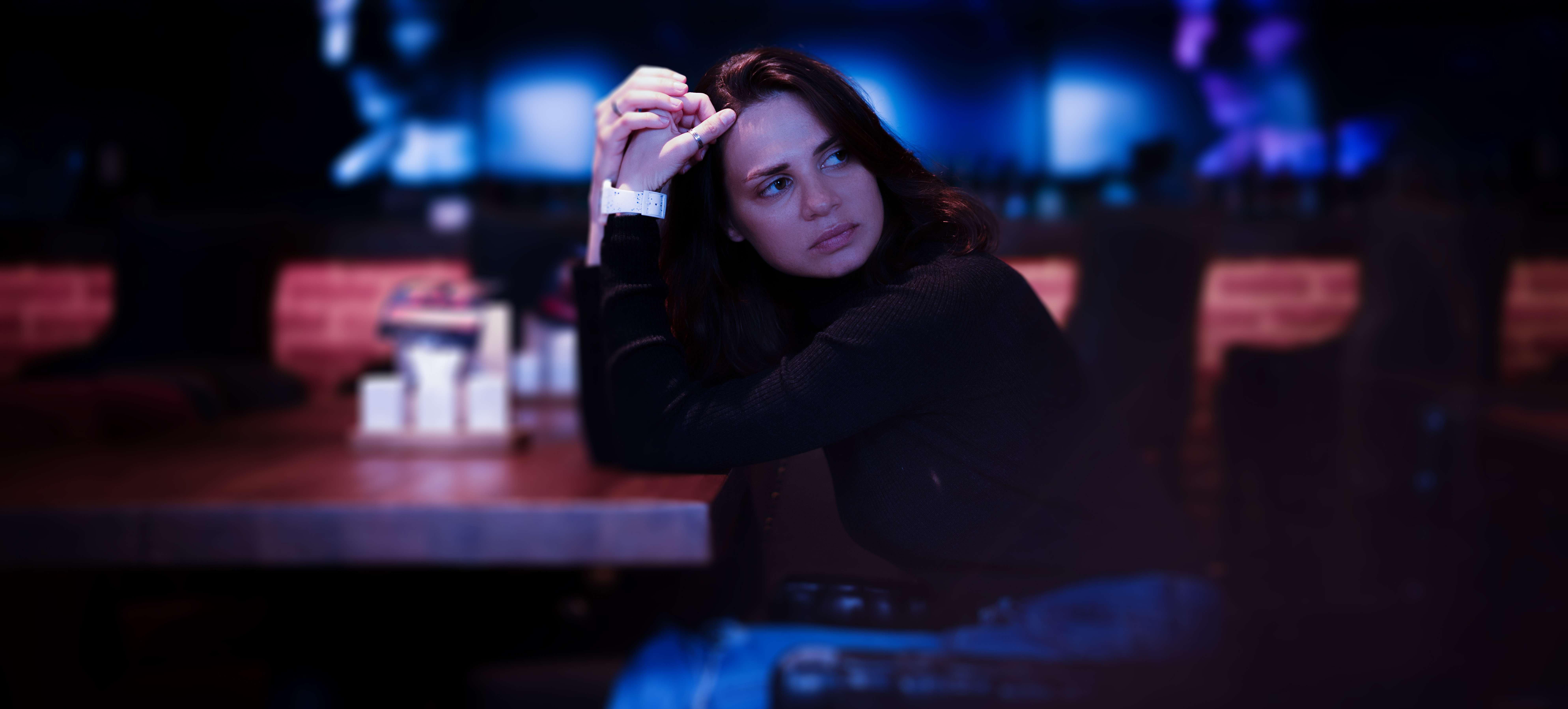 Joven seria y triste sentada sola en un restaurante nocturno. | Fuente: Shutterstock