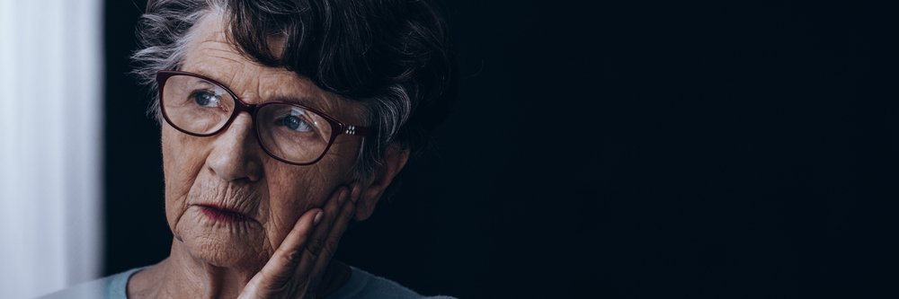 Anciana solitaria con Alzheimer mirando por la ventana. | Fuente: Shutterstock