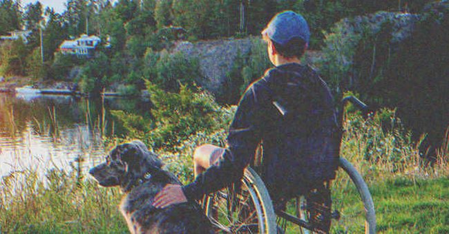 Un chico en silla de ruedas frente a un lago, con su perro. | Foto: Shutterstock