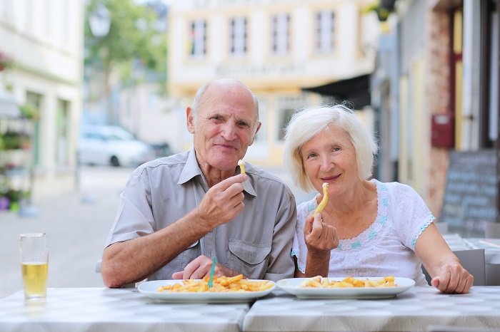 Abuelos comiendo papas a la francesa| Foto: Shutterstock