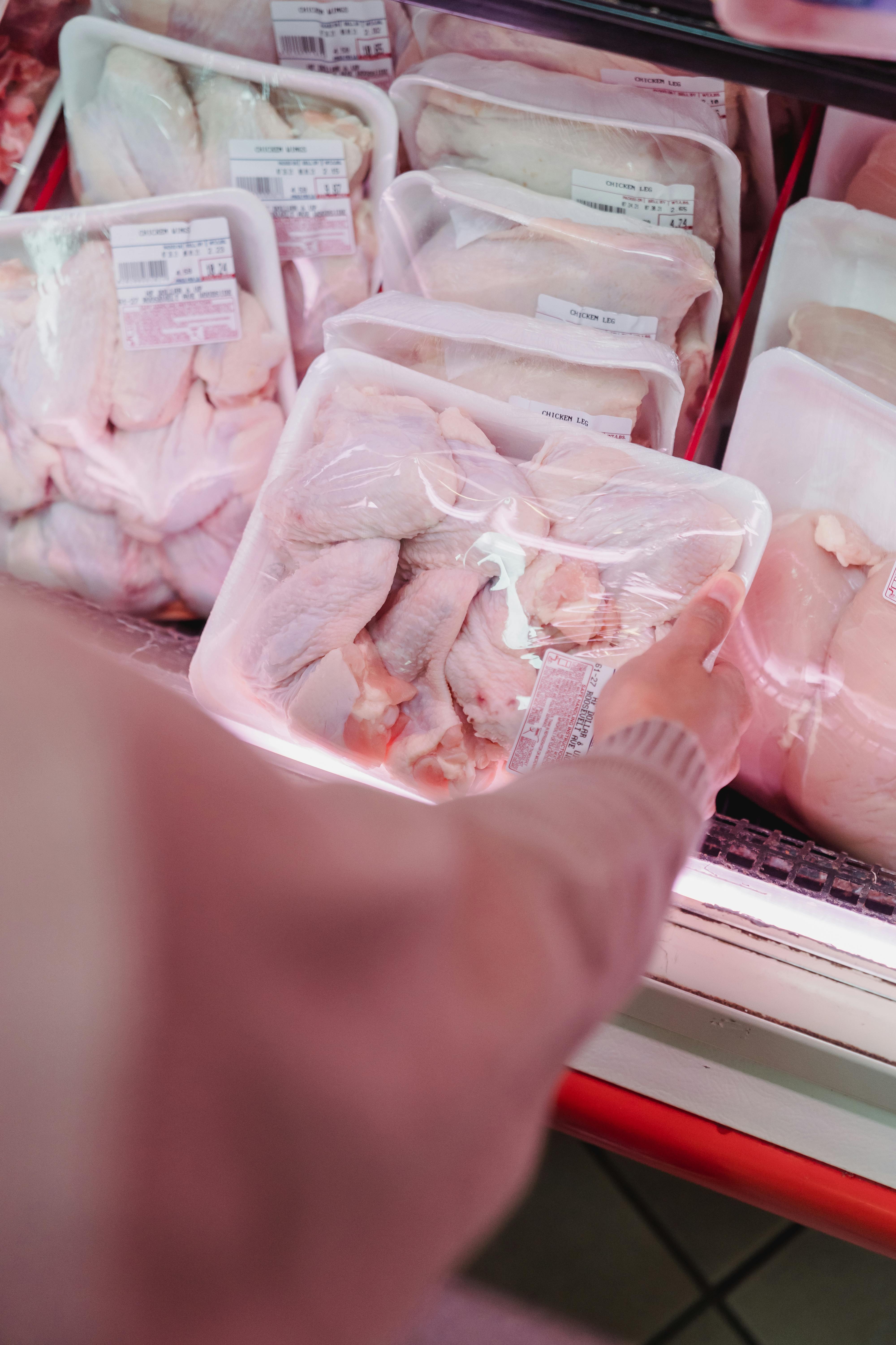 Escogiendo bandejas de pollo en una tienda | Fuente: Pexels