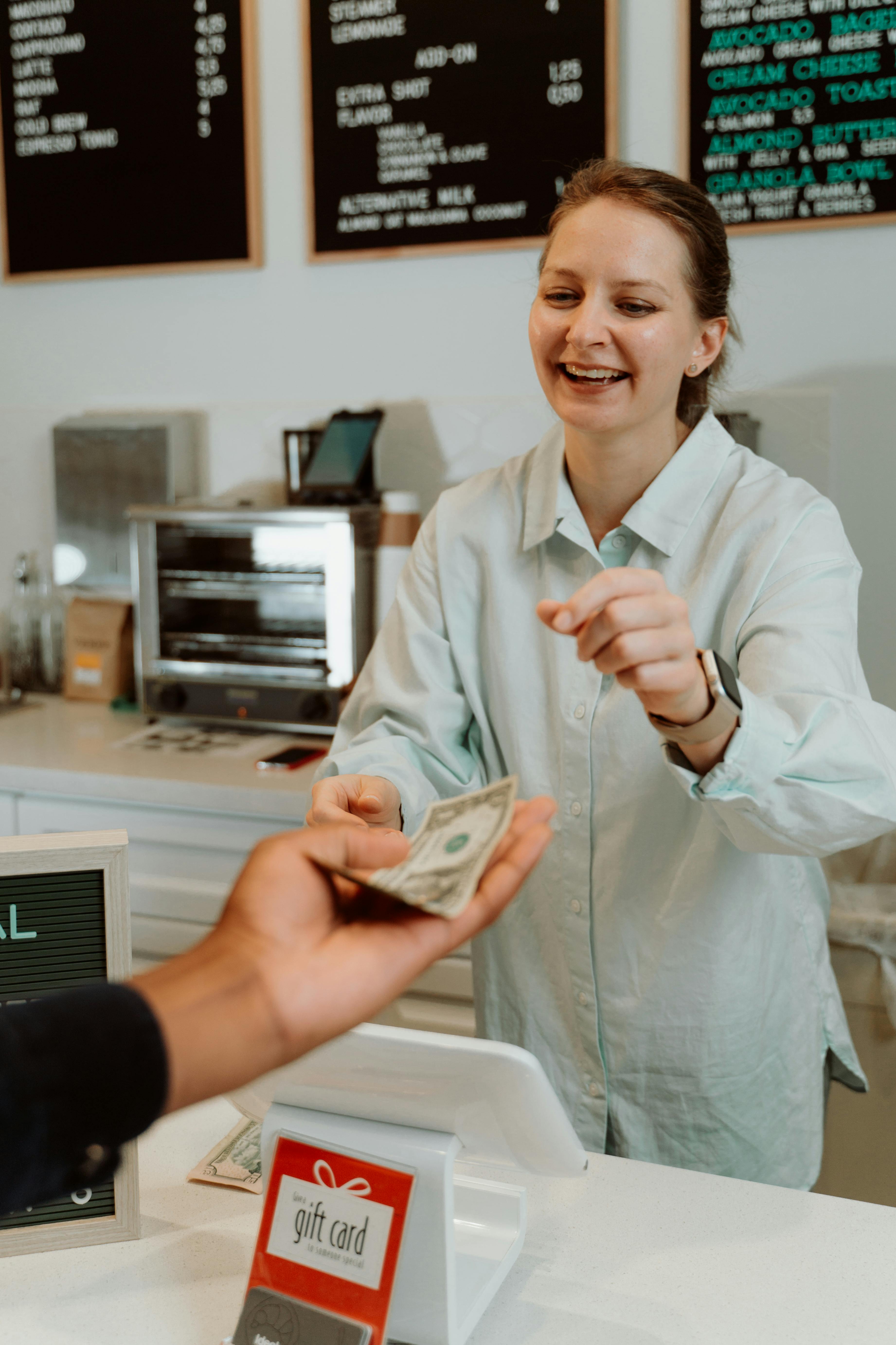 Una mujer recibiendo dinero de un cliente | Fuente: Pexels