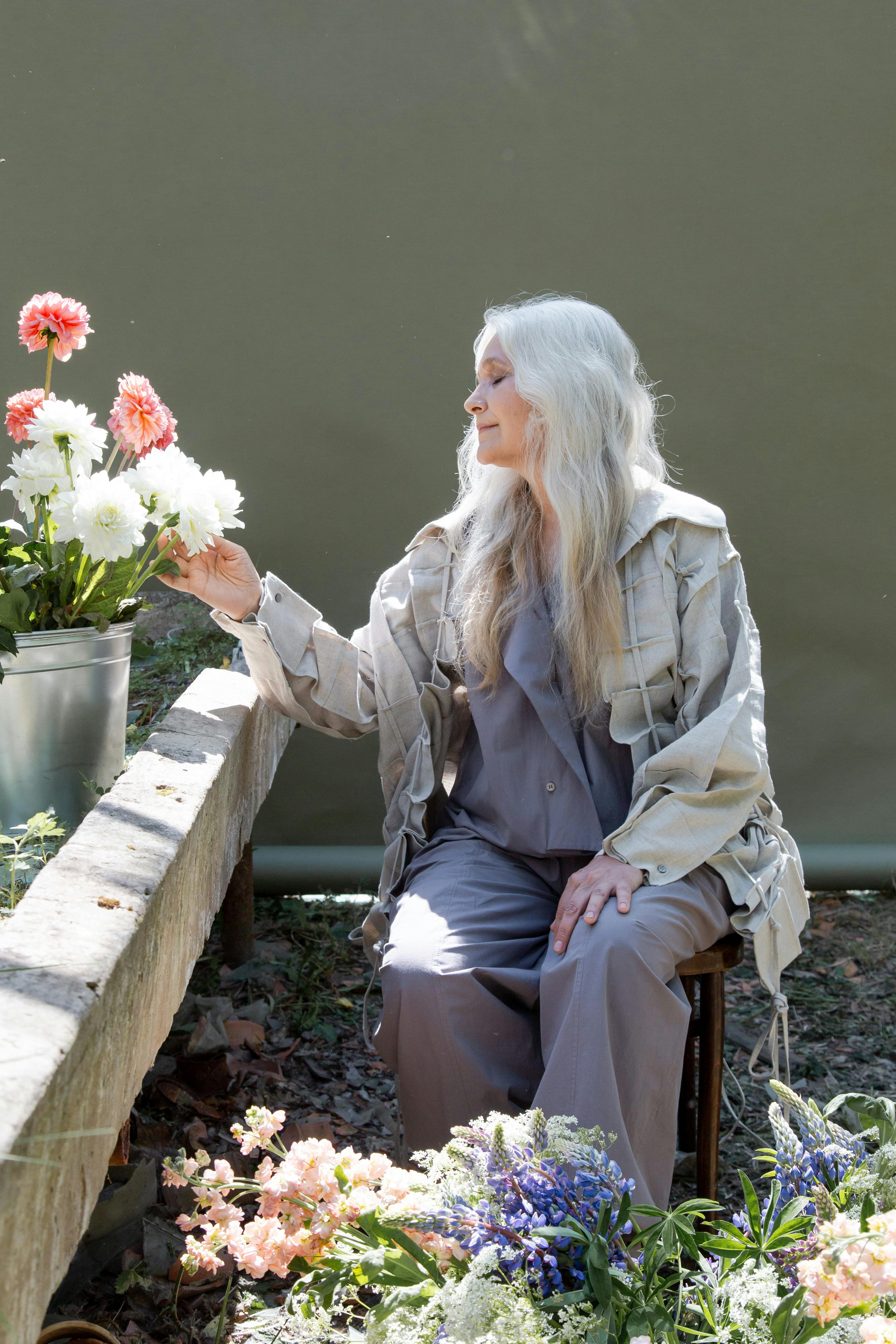 Una anciana posando con flores | Fuente: Pexels