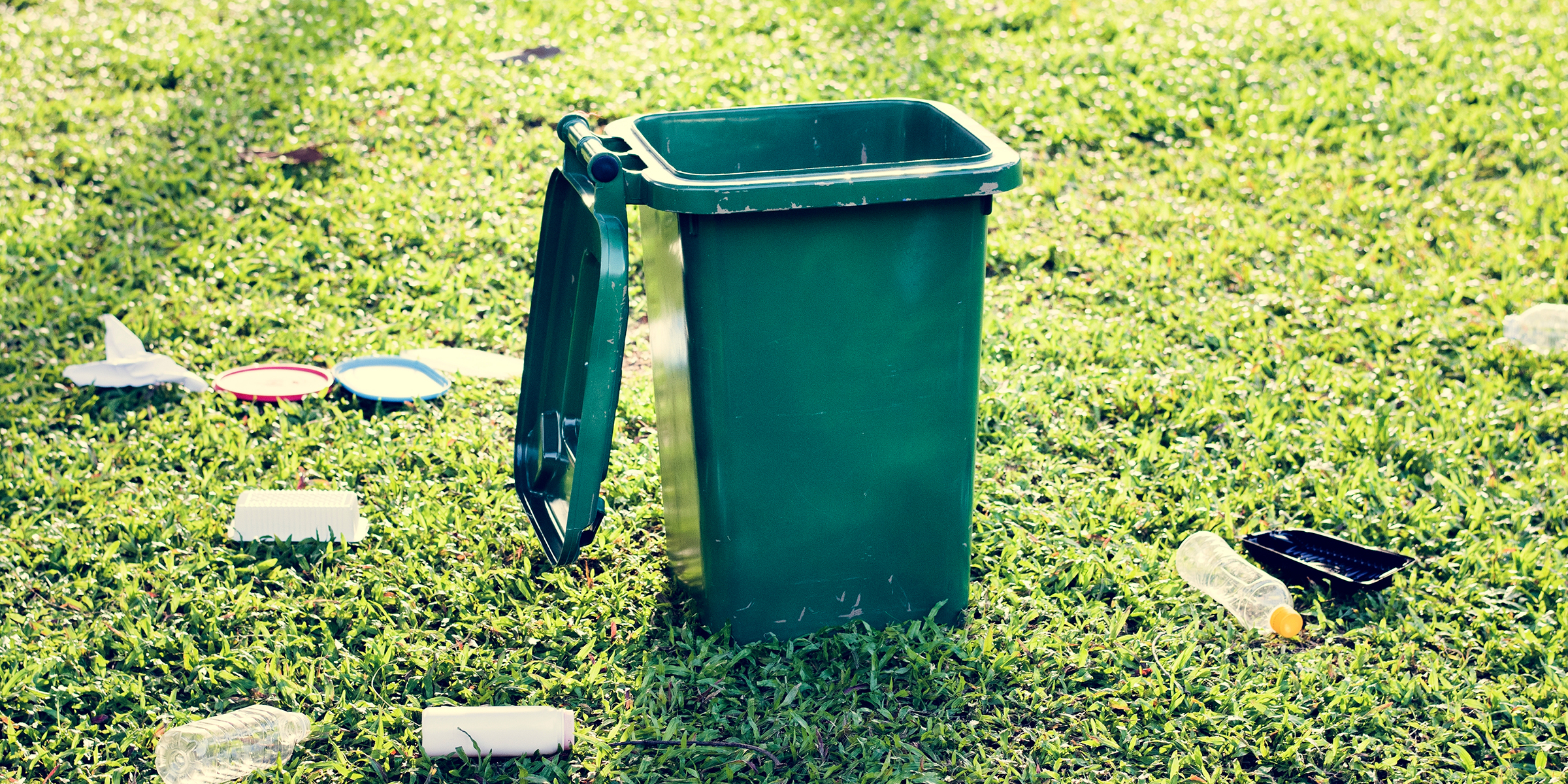 Una papelera y basura sobre el césped | Fuente: Shutterstock