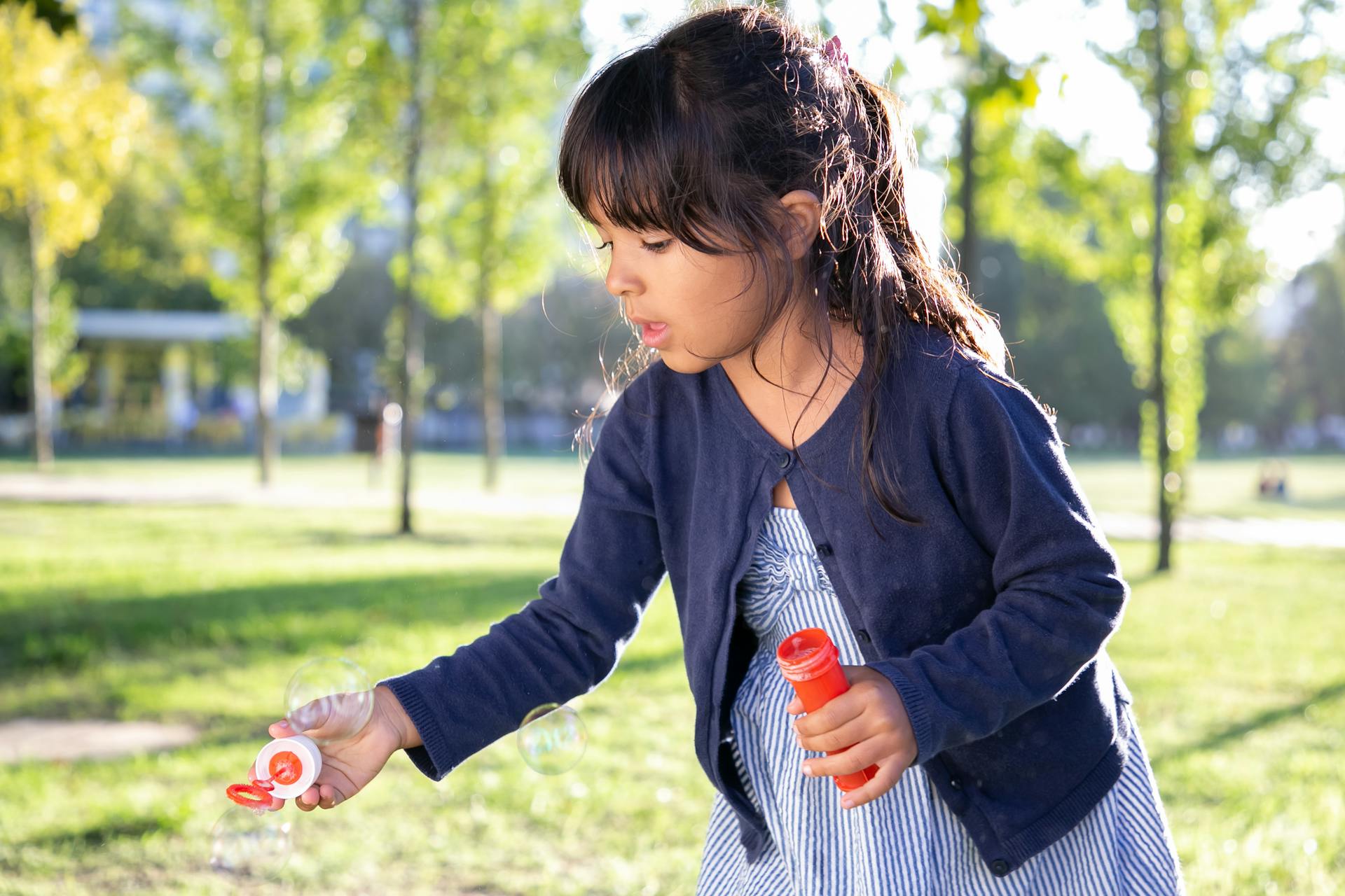 Una niña soplando burbujas en un parque | Fuente: Pexels