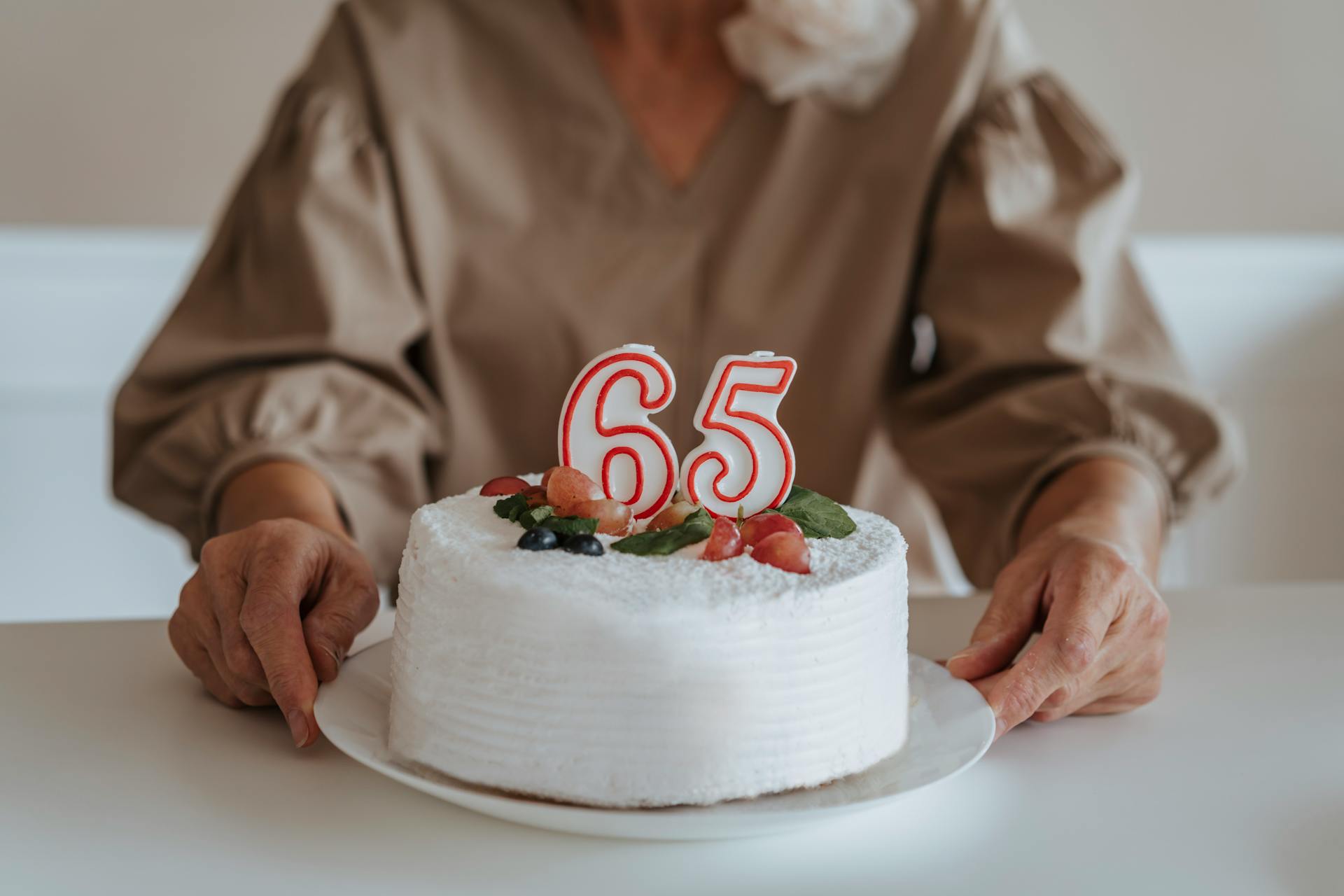 Foto recortada de una mujer mayor sujetando su pastel de 65º cumpleaños | Fuente: Pexels