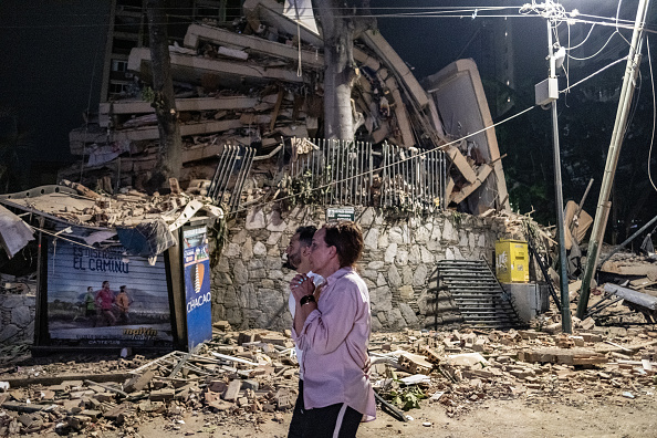 Habitantes permanecen junto a los escombros de un edificio colapsado tras el fuerte terremoto ocurrido en Caracas, Venezuela, el 24 de junio de 2026. Después de los dos sismos de magnitudes 7,2 y 7,5 que sacudieron la costa norte del Caribe venezolano, el país declaró el estado de emergencia nacional. Los movimientos telúricos provocaron graves daños, afectaron el transporte y dieron lugar a alertas de tsunami en la región.