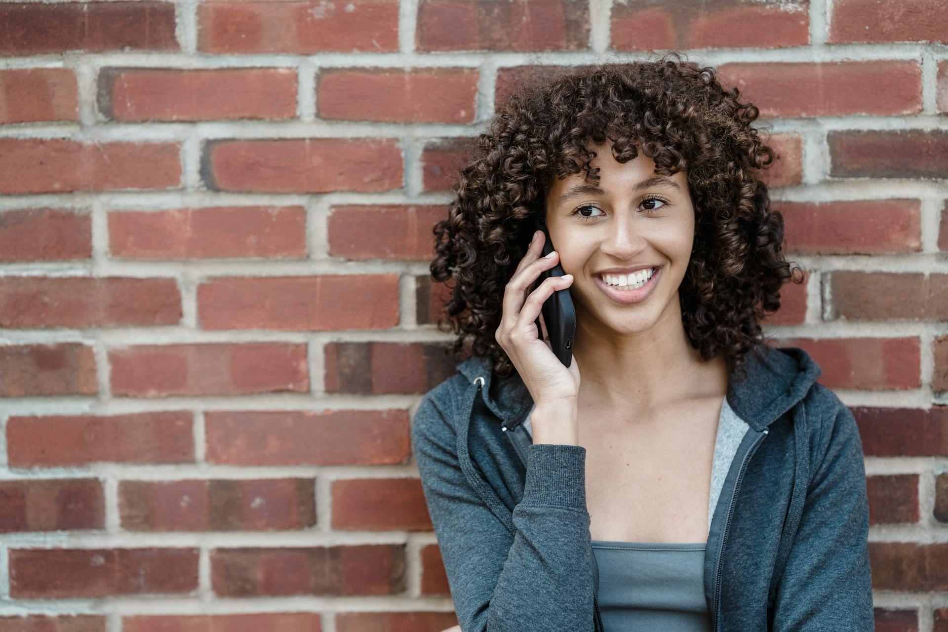 Una mujer sonriendo mientras habla por teléfono | Fuente: Pexels