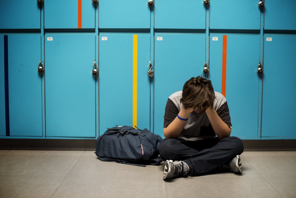 Estudiante llorando en pasillo de la escuela.|Fuente: Shutterstock