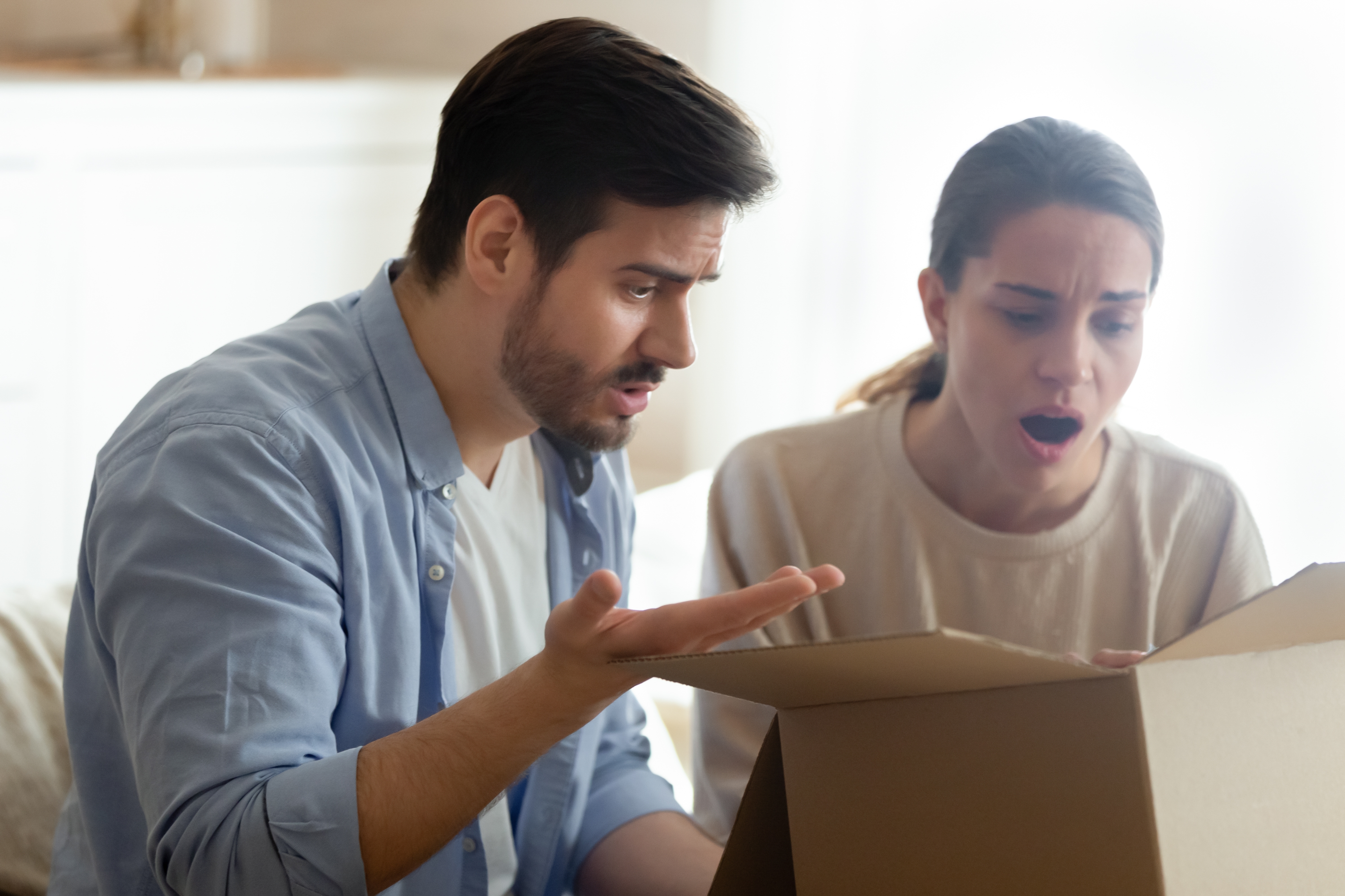 Una pareja molesta mirando una caja de reparto | Fuente: Shutterstock