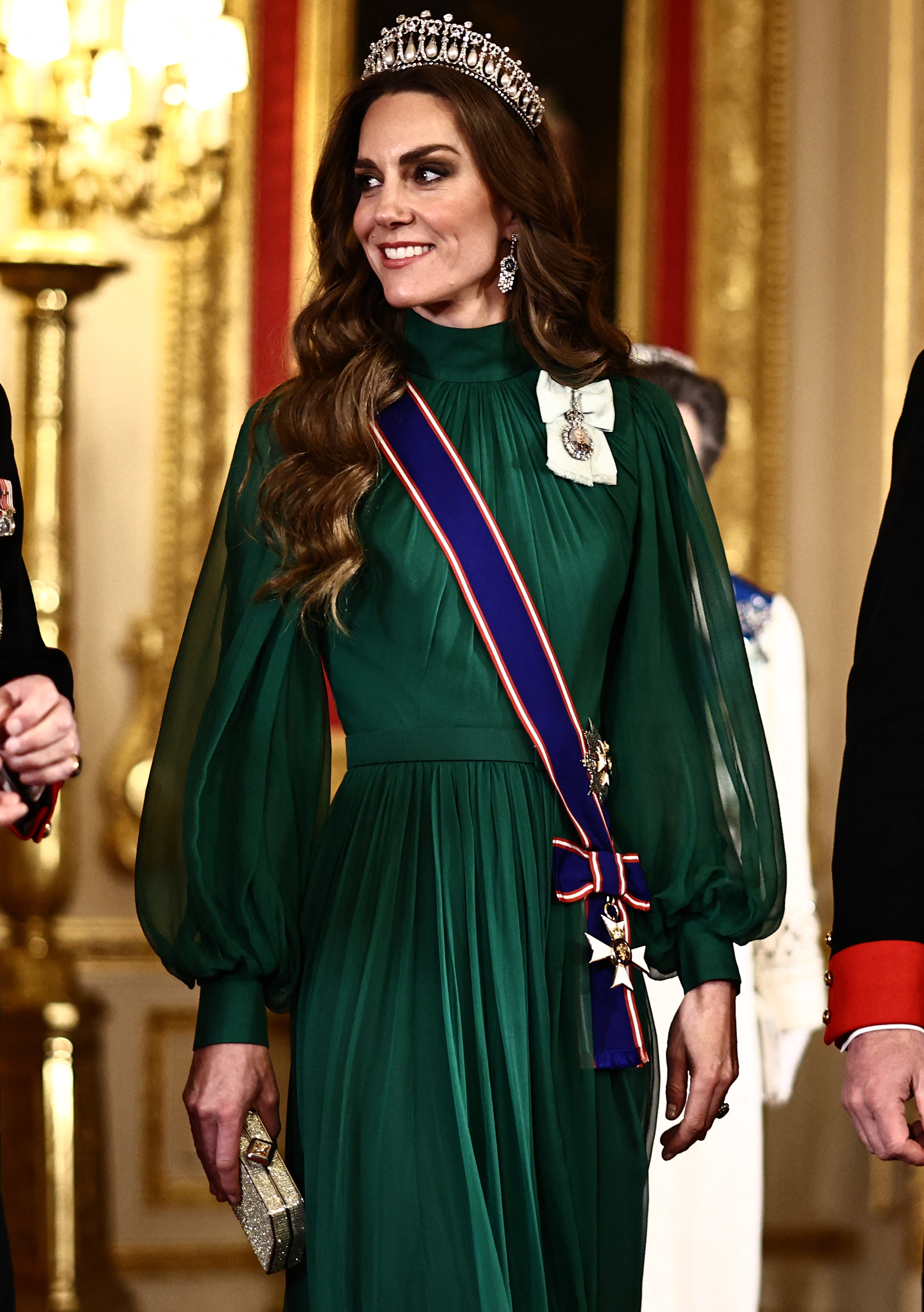 Catherine, princesa de Gales, llega al banquete de Estado en el salón de San Jorge del castillo de Windsor el 18 de marzo de 2026, en honor al presidente de Nigeria. Luce un vestido de gasa verde esmeralda de Emilia Wickstead, con cuello alto fruncido y mangas obispo amplias y transparentes. Lo complementa con la tiara Lover's Knot de la reina Mary, pendientes colgantes de diamantes, bolso de mano dorado brillante, banda de la Real Orden Victoriana y Orden de la Familia Real del rey Charles III. | Fuente: Getty Images