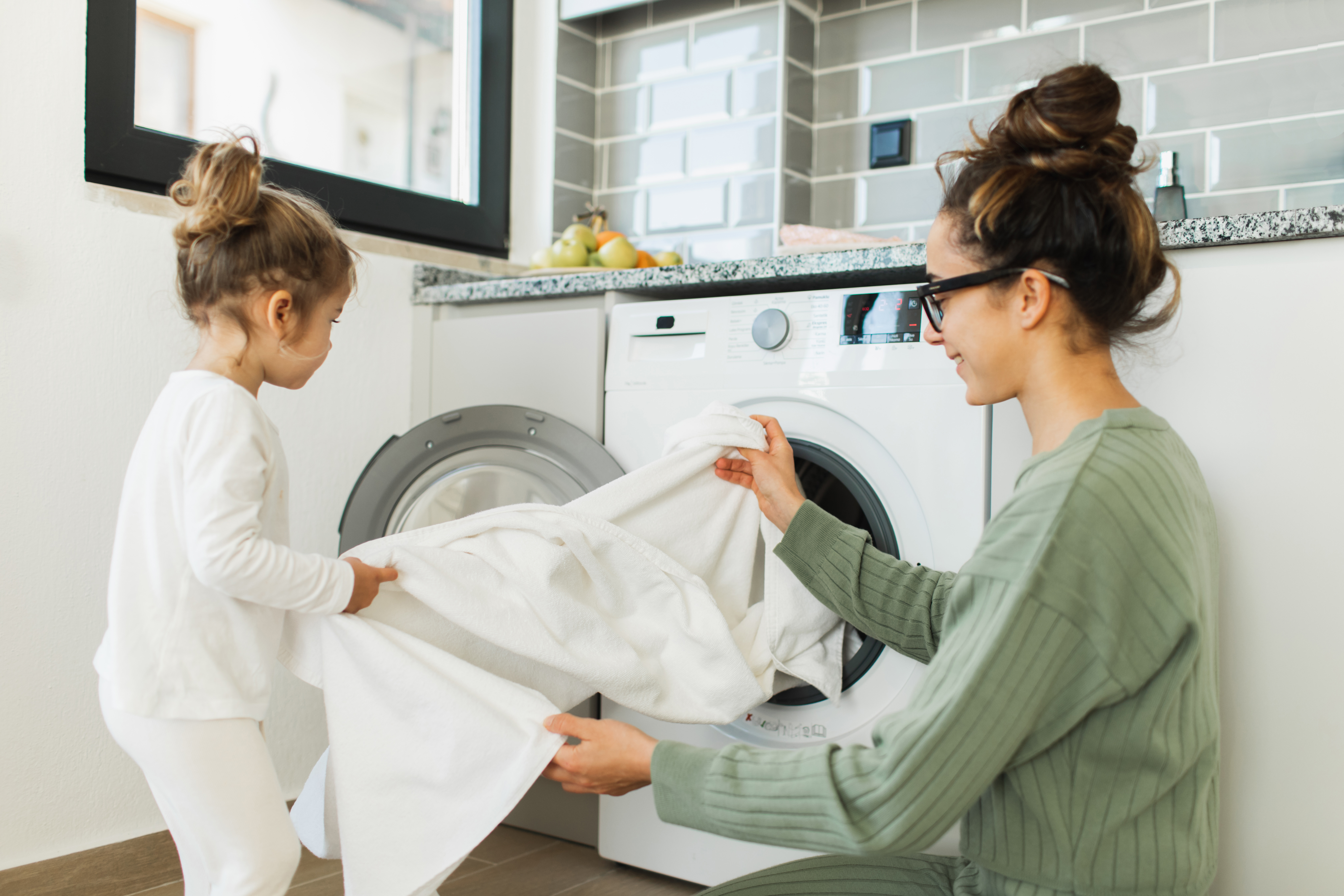 Madre y niña cargando lavadora | Foto: Getty Images