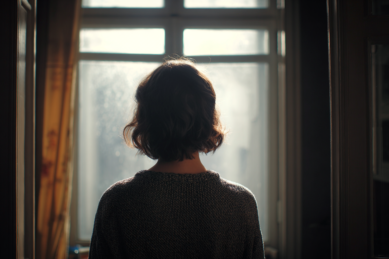 Una donna in piedi vicino a una finestra | Fonte: Midjourney