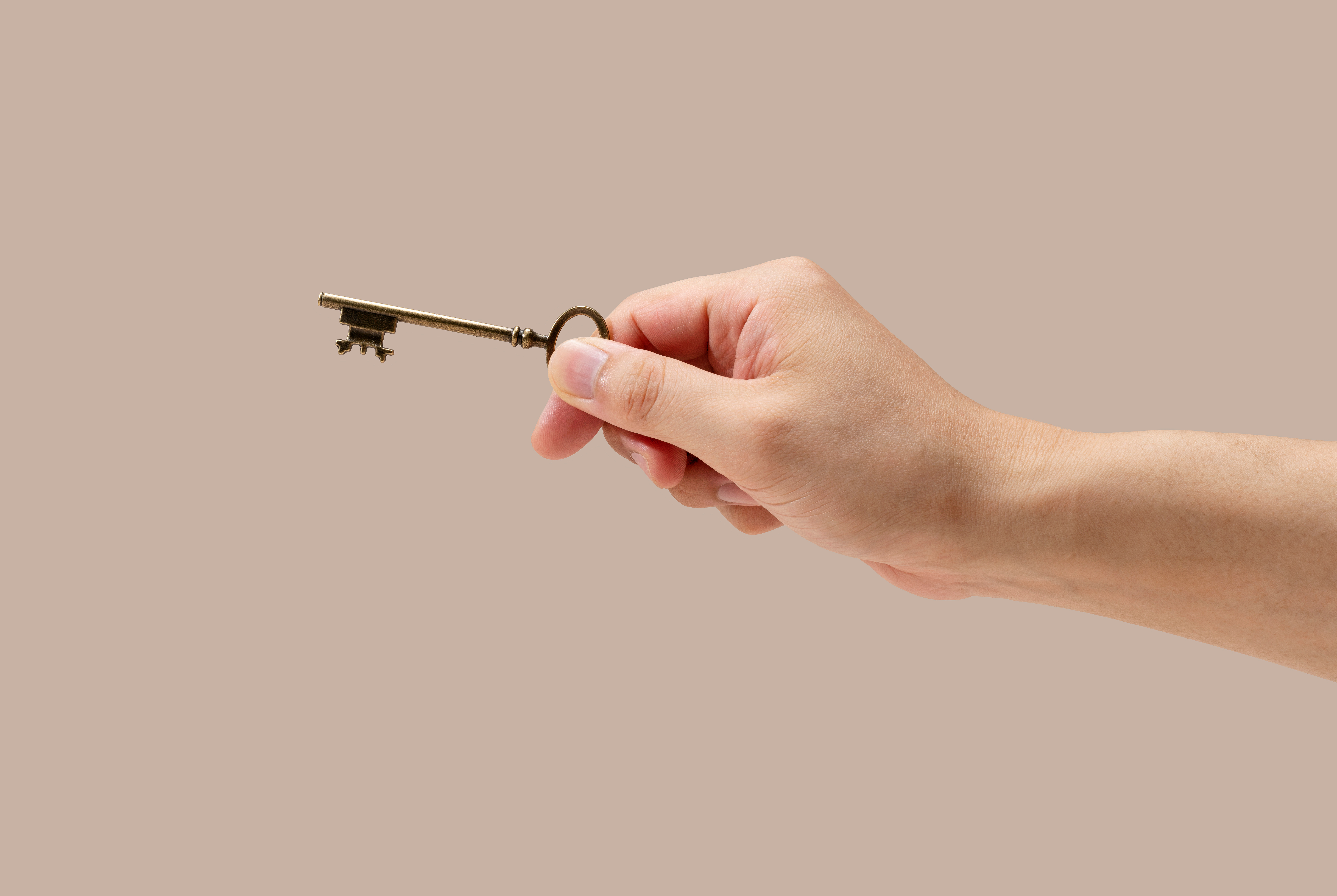 La mano de un hombre sujetando una llave de latón | Fuente: Shutterstock