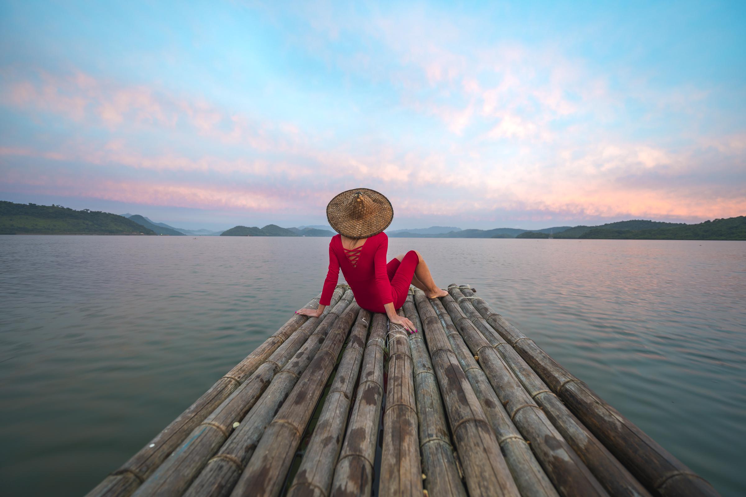 Mujer con vestido rojo y sombrero tradicional sentada en una balsa de madera | Fuente: Getty Images