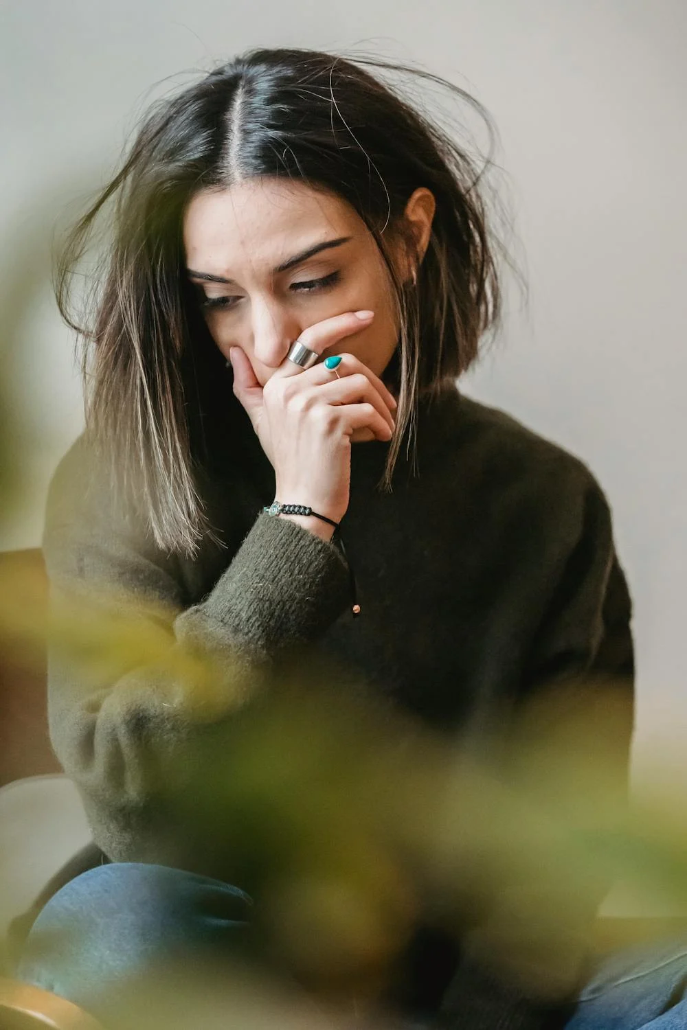 Una mujer triste mirando hacia abajo ⏐ Fuente: Pexels