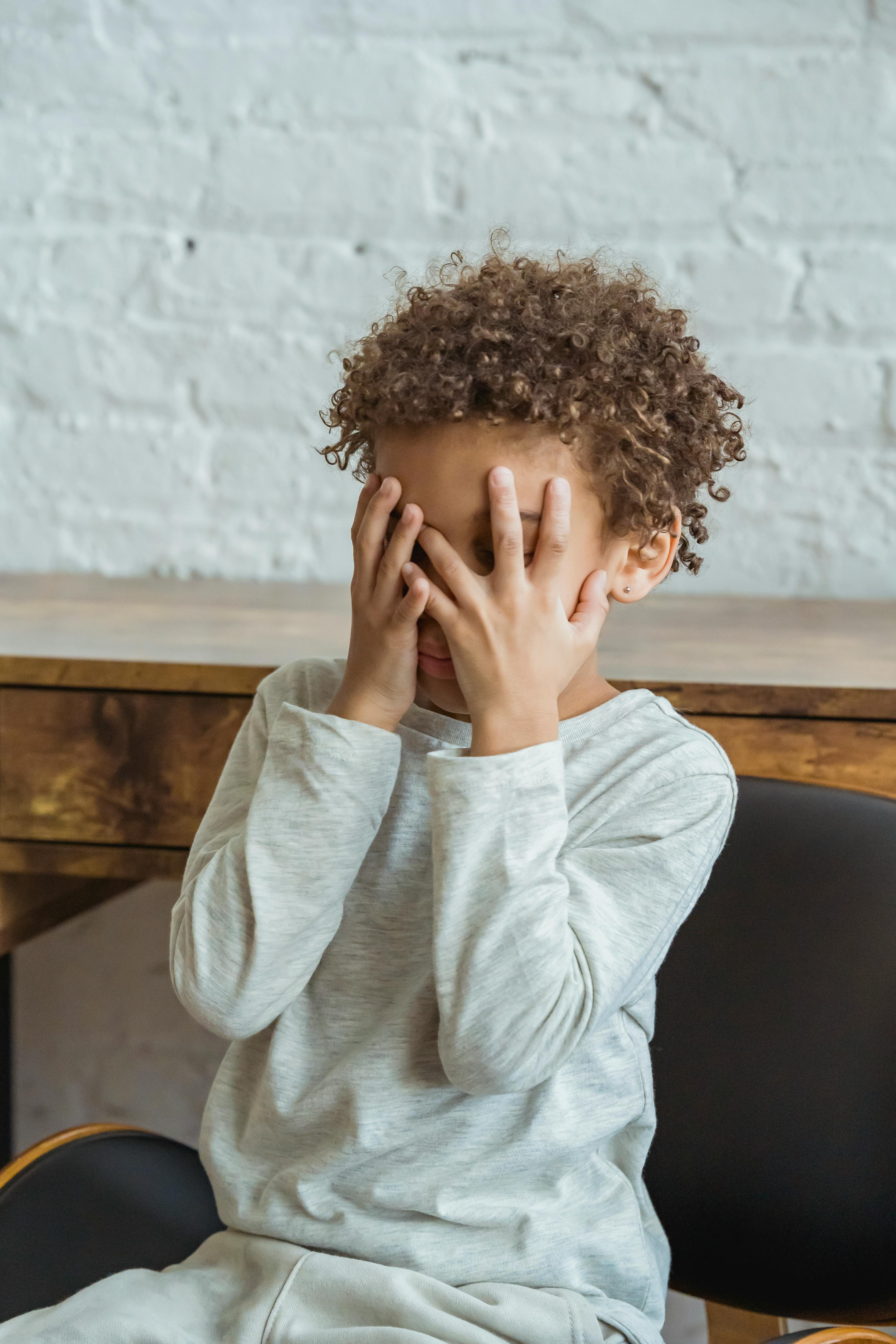 Un niño cubriéndose la cara con las palmas de las manos | Fuente: Pexels