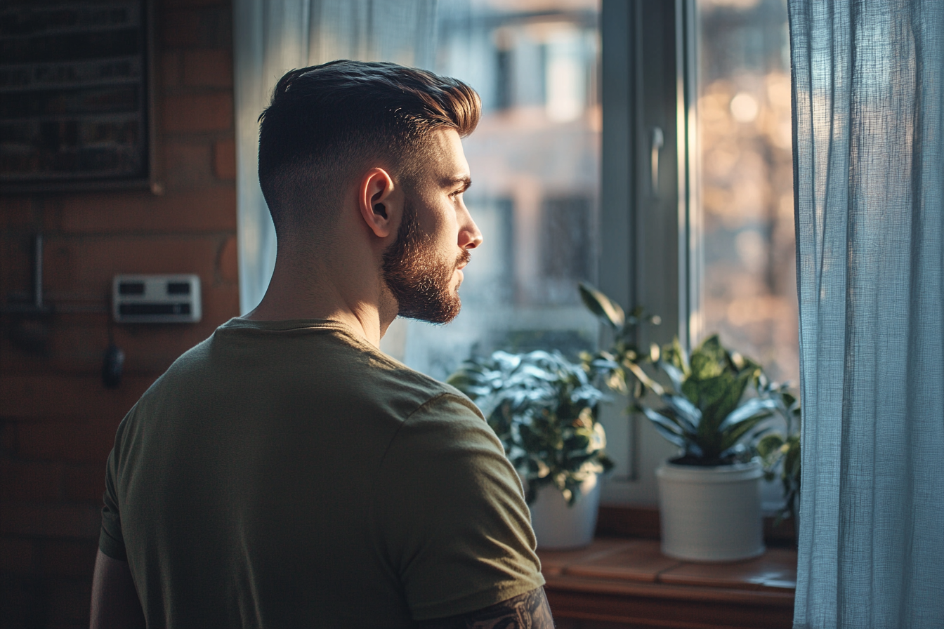 Un hombre mirando por la ventana | Fuente: Midjourney