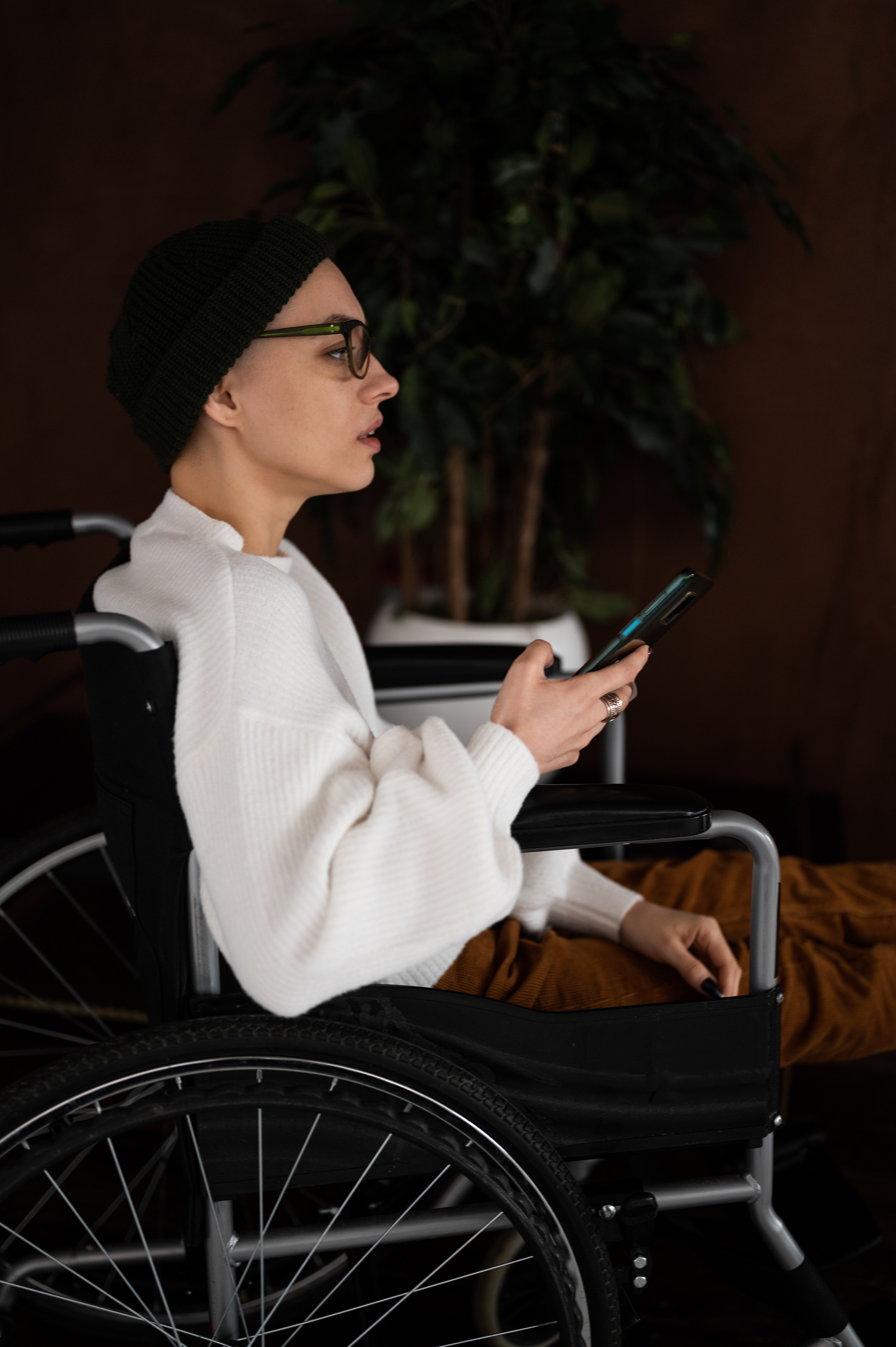 Mujer en silla de ruedas con un teléfono en la mano. | Foto: Pexels