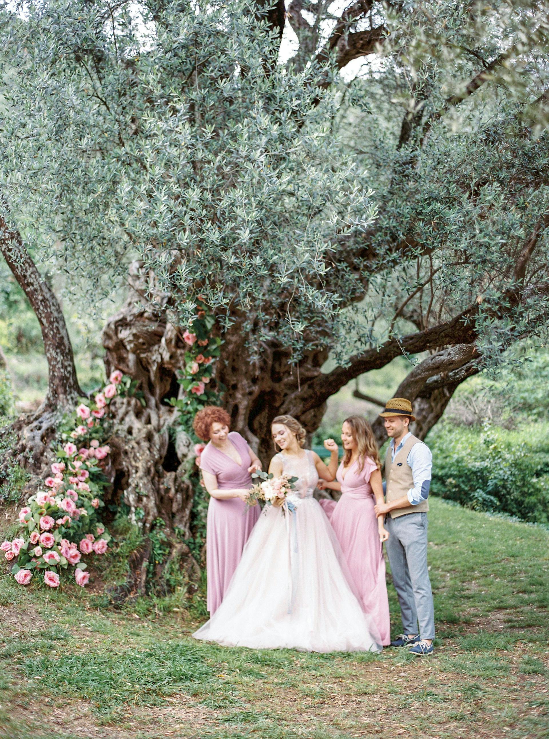 Una novia posando para las fotos con su familia bajo un árbol | Fuente: Pexels