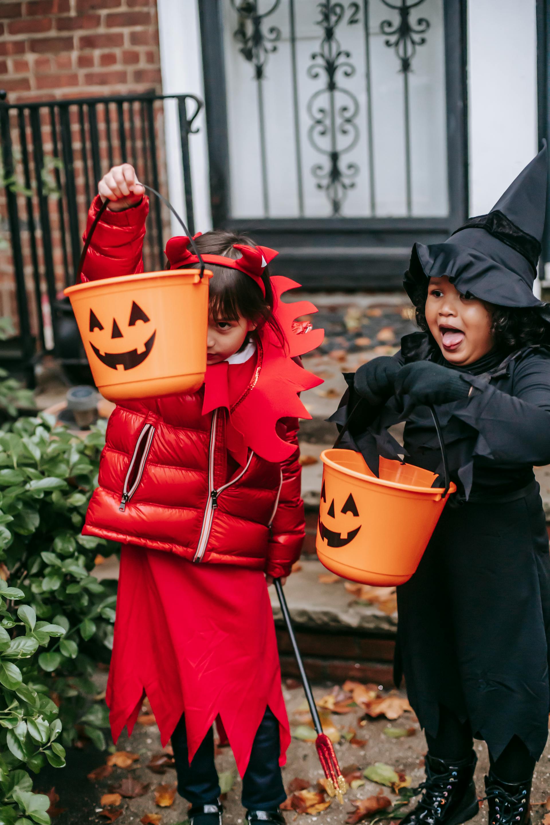 Niños pidiendo dulces con disfraces de Halloween cerca de la entrada de una casa | Fuente: Pexels