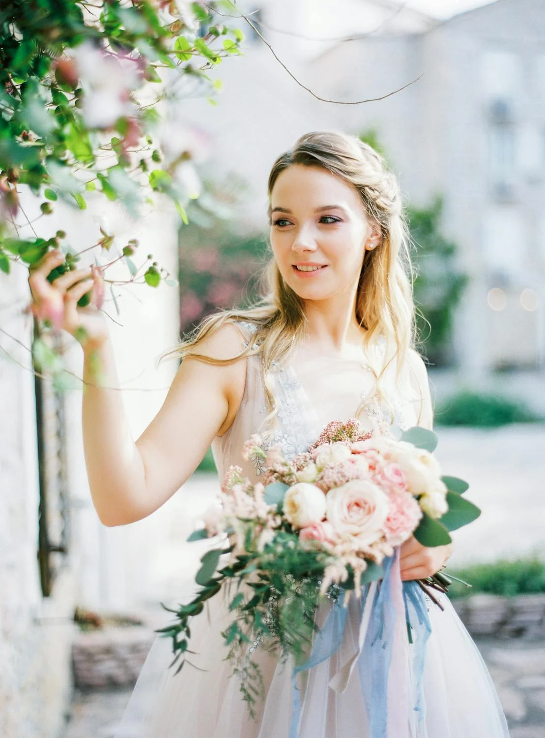 Una novia sonriente tocando flores | Fuente: Pexels