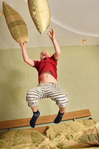 Niño saltando y jugando en una cama. Fuente: Shutterstock