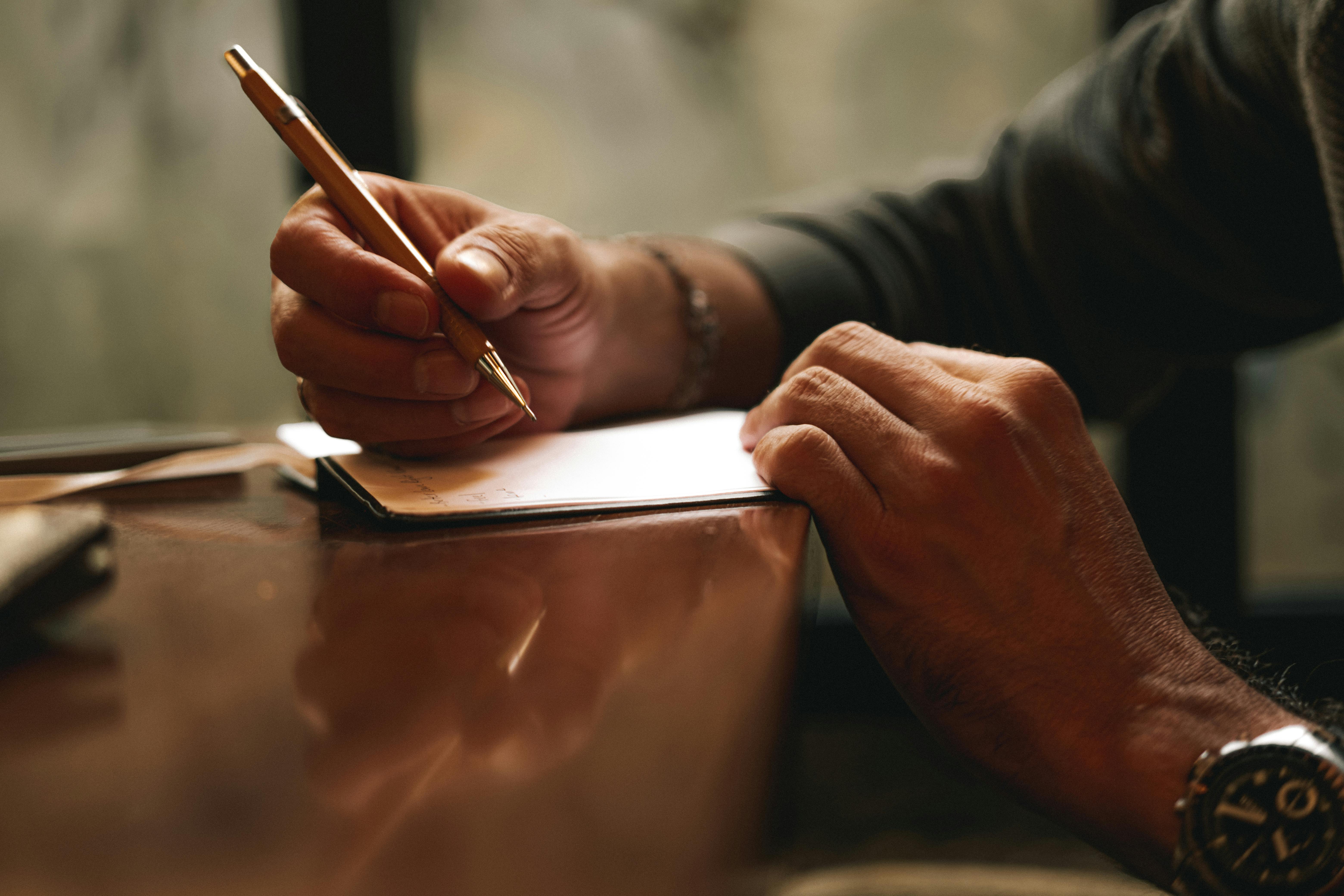 Una persona escribiendo en un papel | Fuente: Pexels
