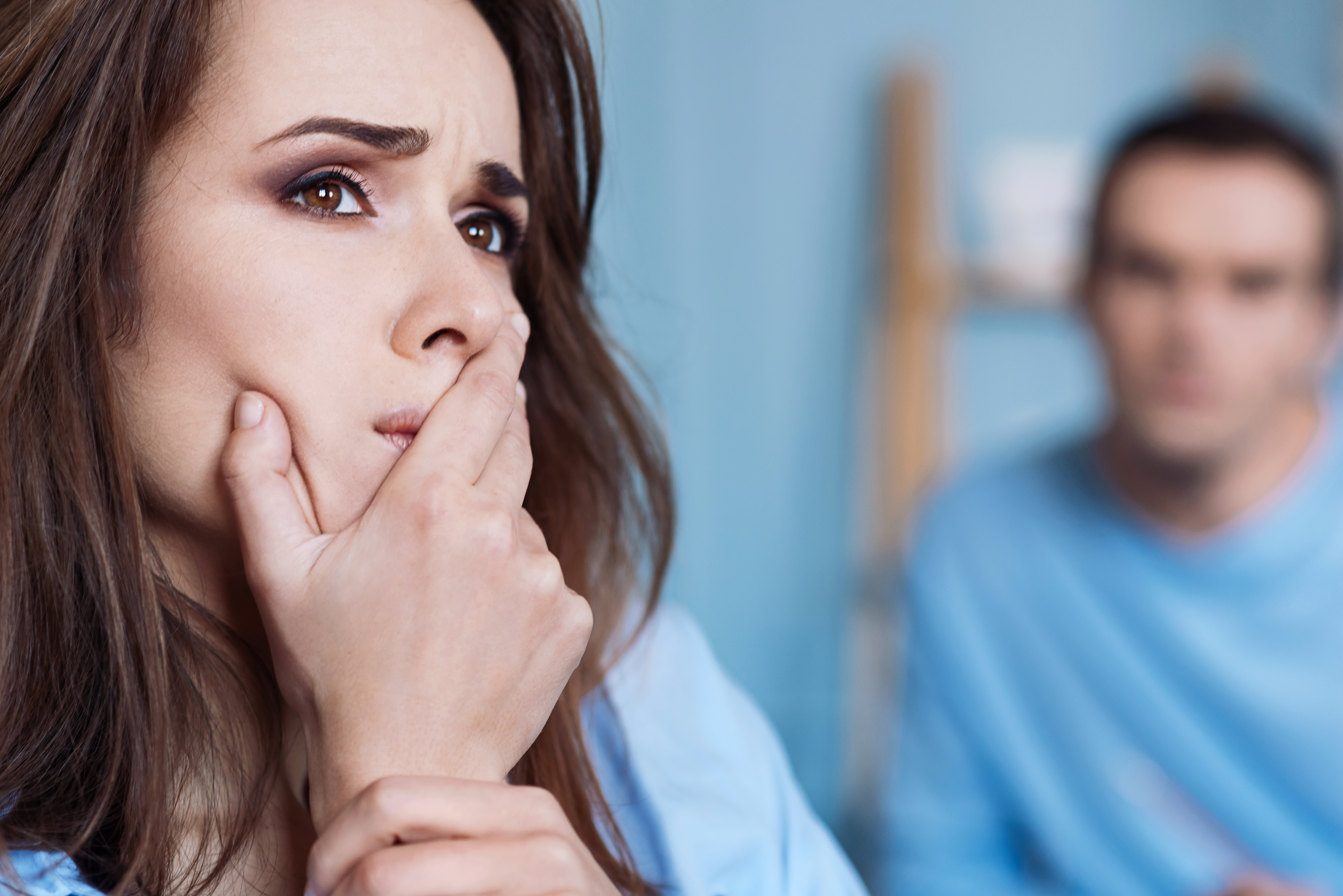 Una mujer sumida en sus pensamientos con su marido al fondo | Foto: Shutterstock