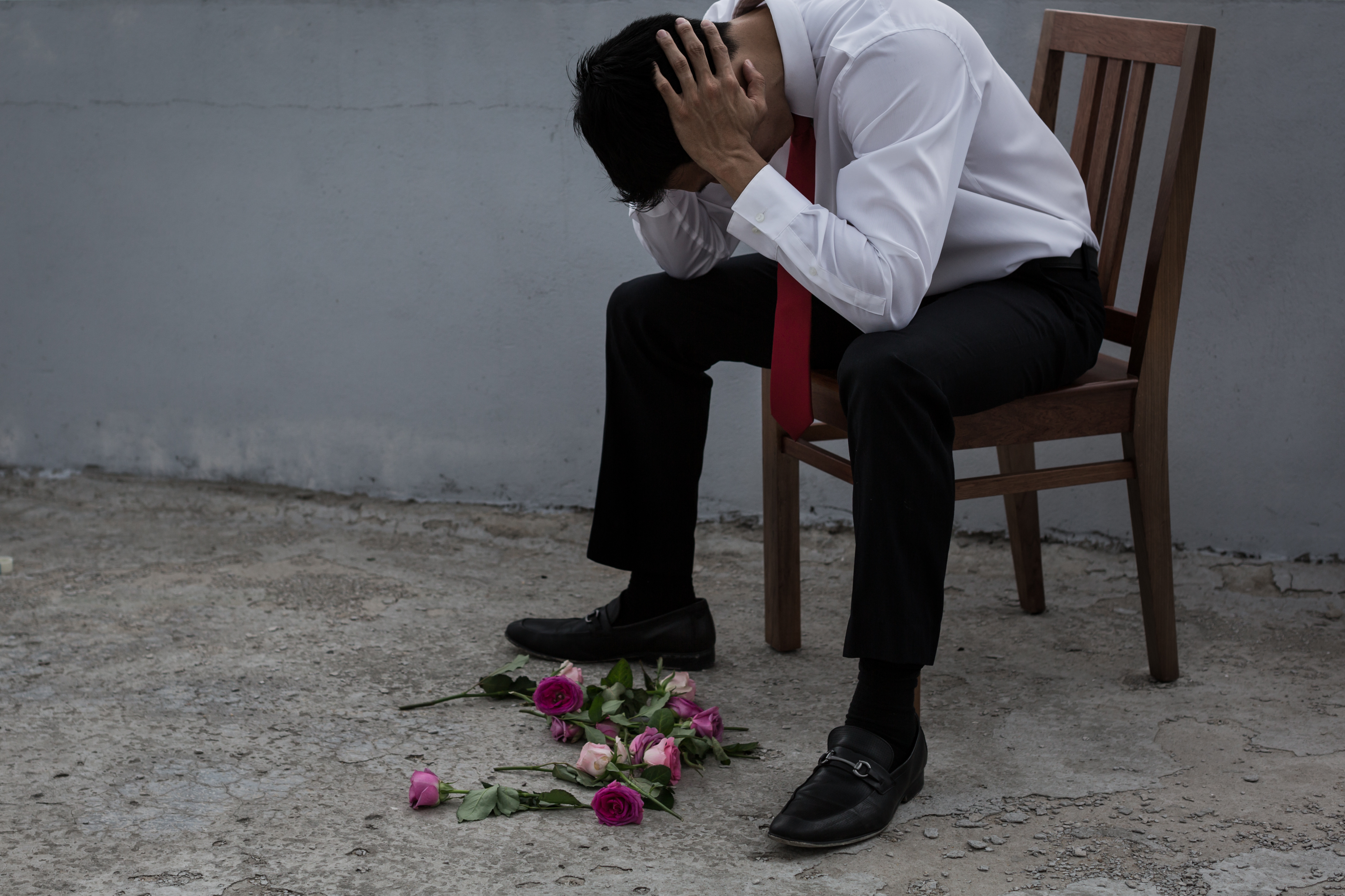 Un hombre con mirada triste y flores esparcidas por el suelo | Foto: Shutterstock