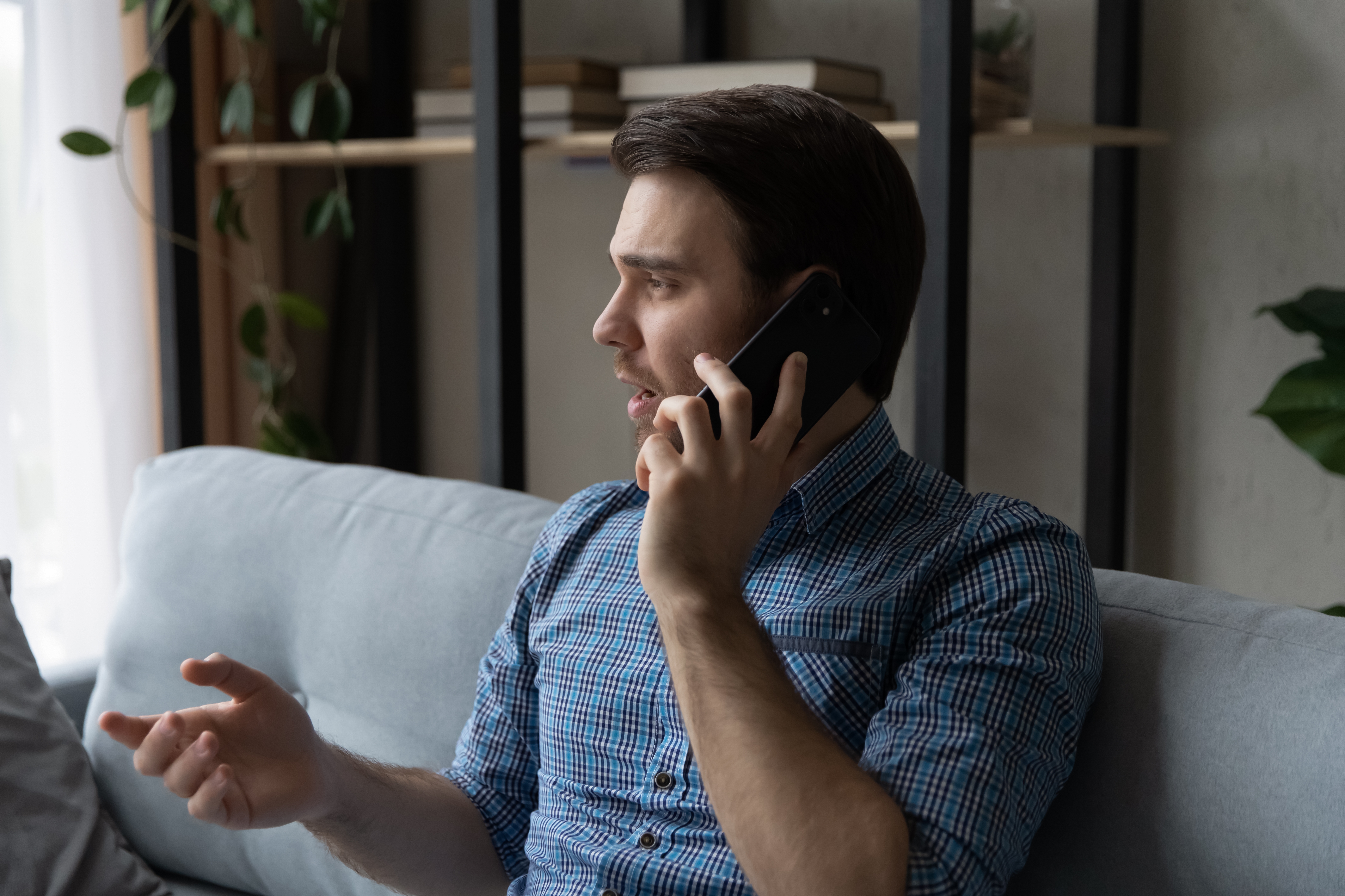Serio usuario reflexivo de teléfono móvil haciendo una llamada desde casa, hablando por el móvil. | Fuente: Shutterstock