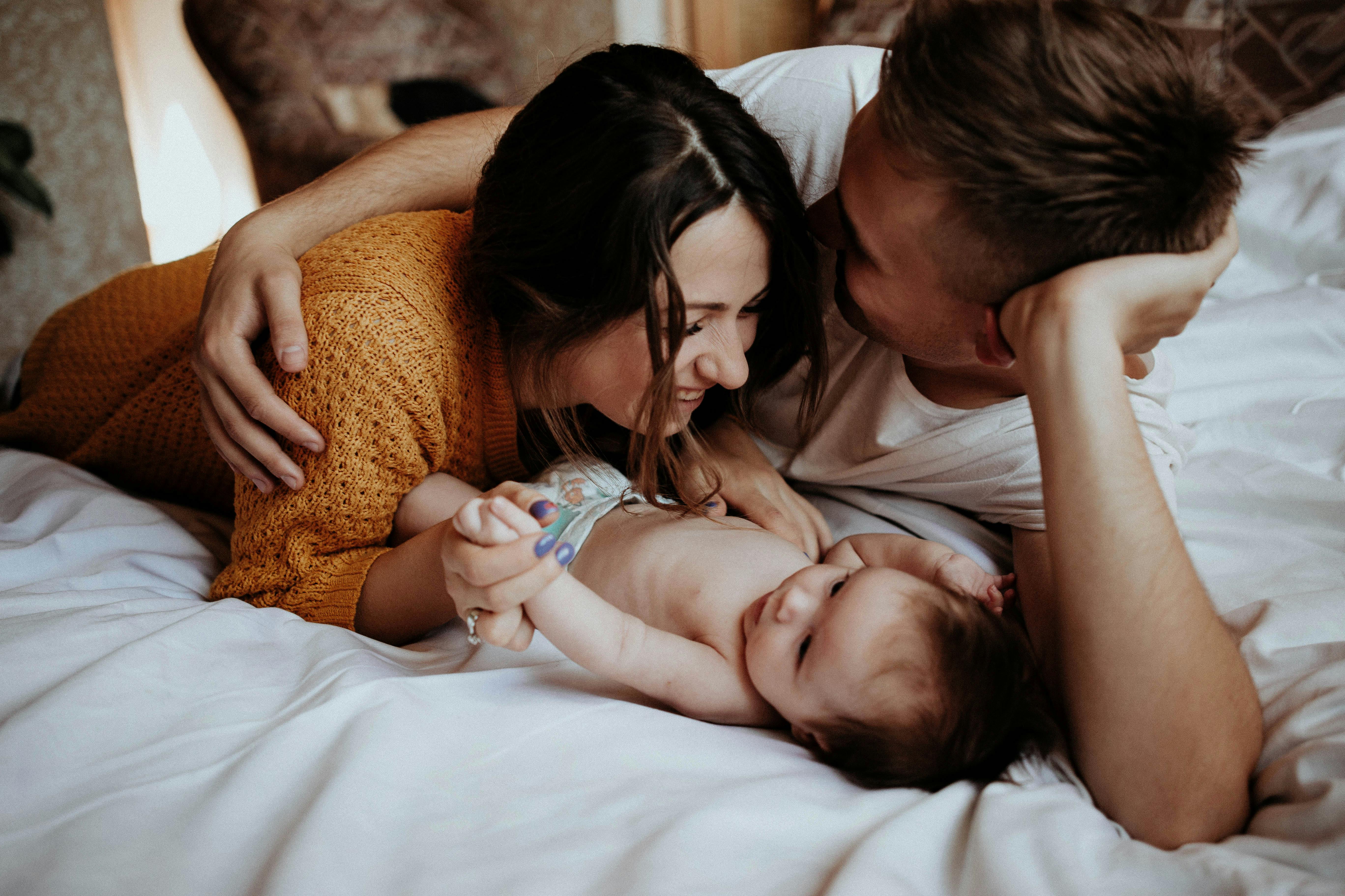 Una pareja feliz estrechando lazos con su bebé | Fuente: Pexels