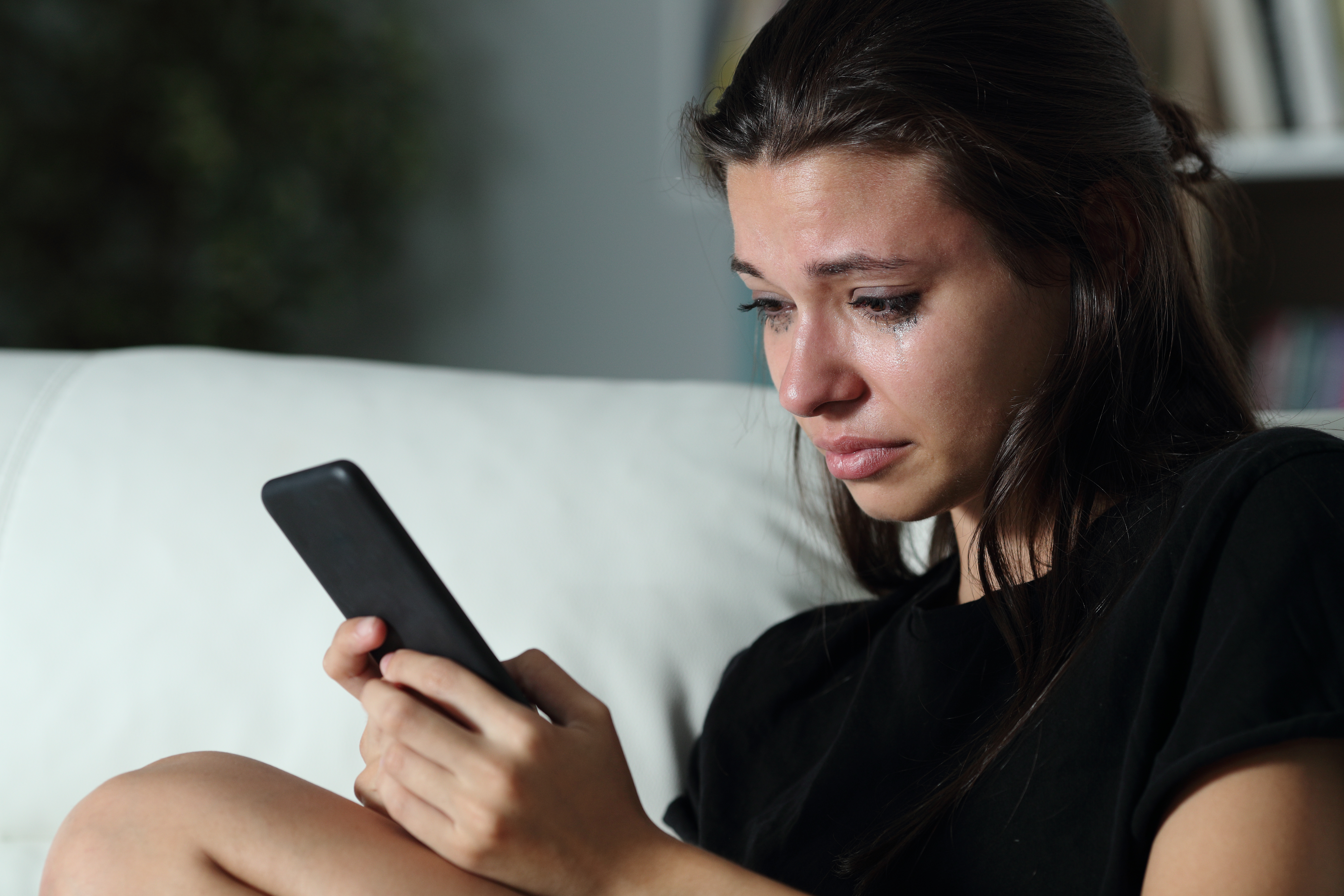Una joven llora mientras mira su móvil. | Foto: Shutterstock