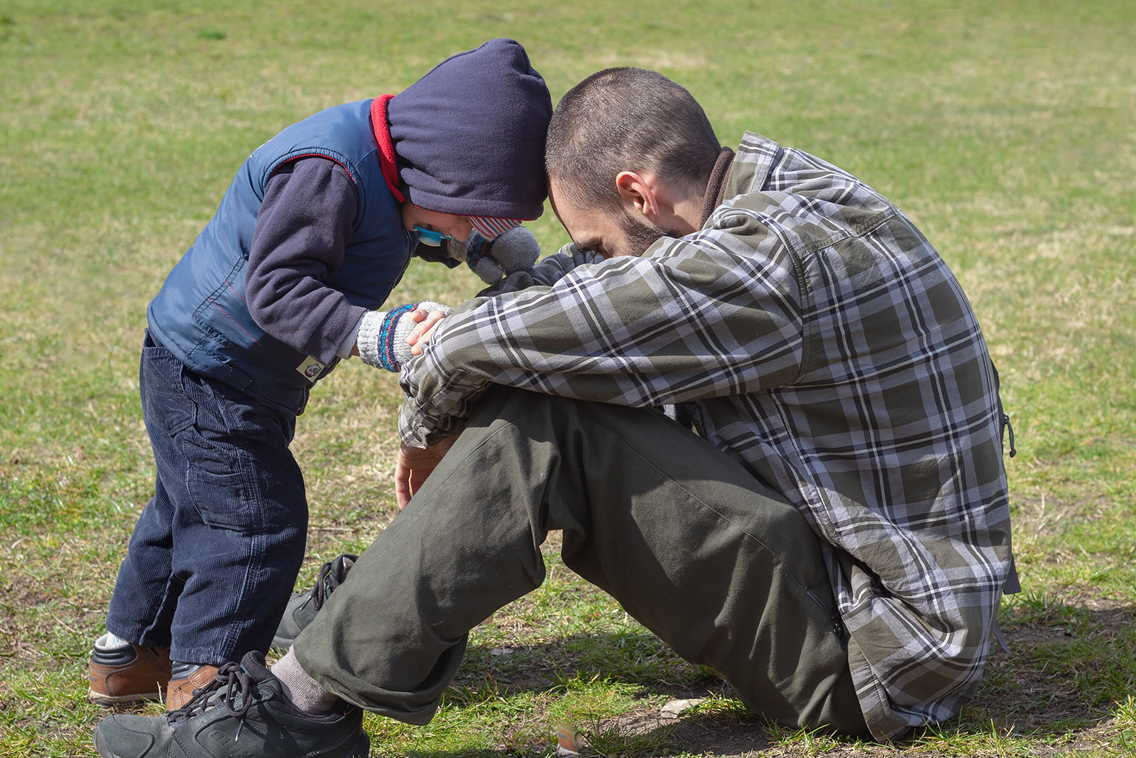 Un padre y su hijo sentados en un campo cubierto de hierba | Fuente: Flickr