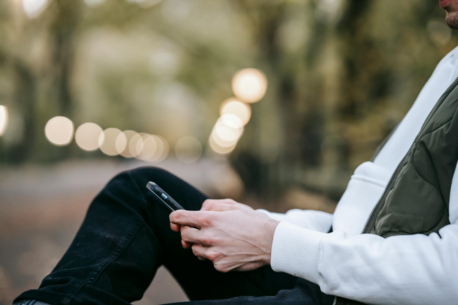 Un hombre sentado en un banco y con un teléfono en la mano | Fuente: Pexels