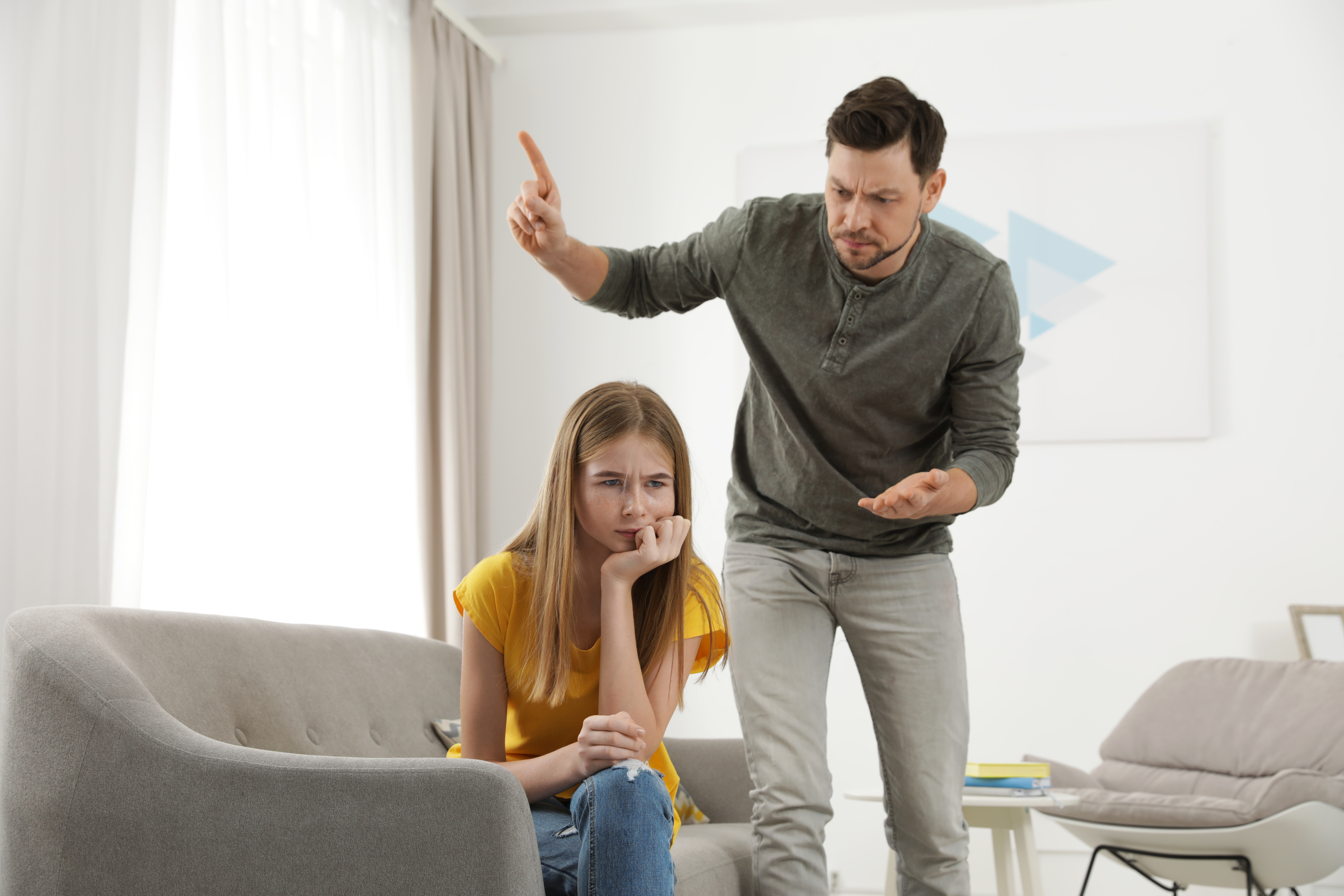 Un hombre regañando a una chica dentro de un salón | Foto: Shutterstock