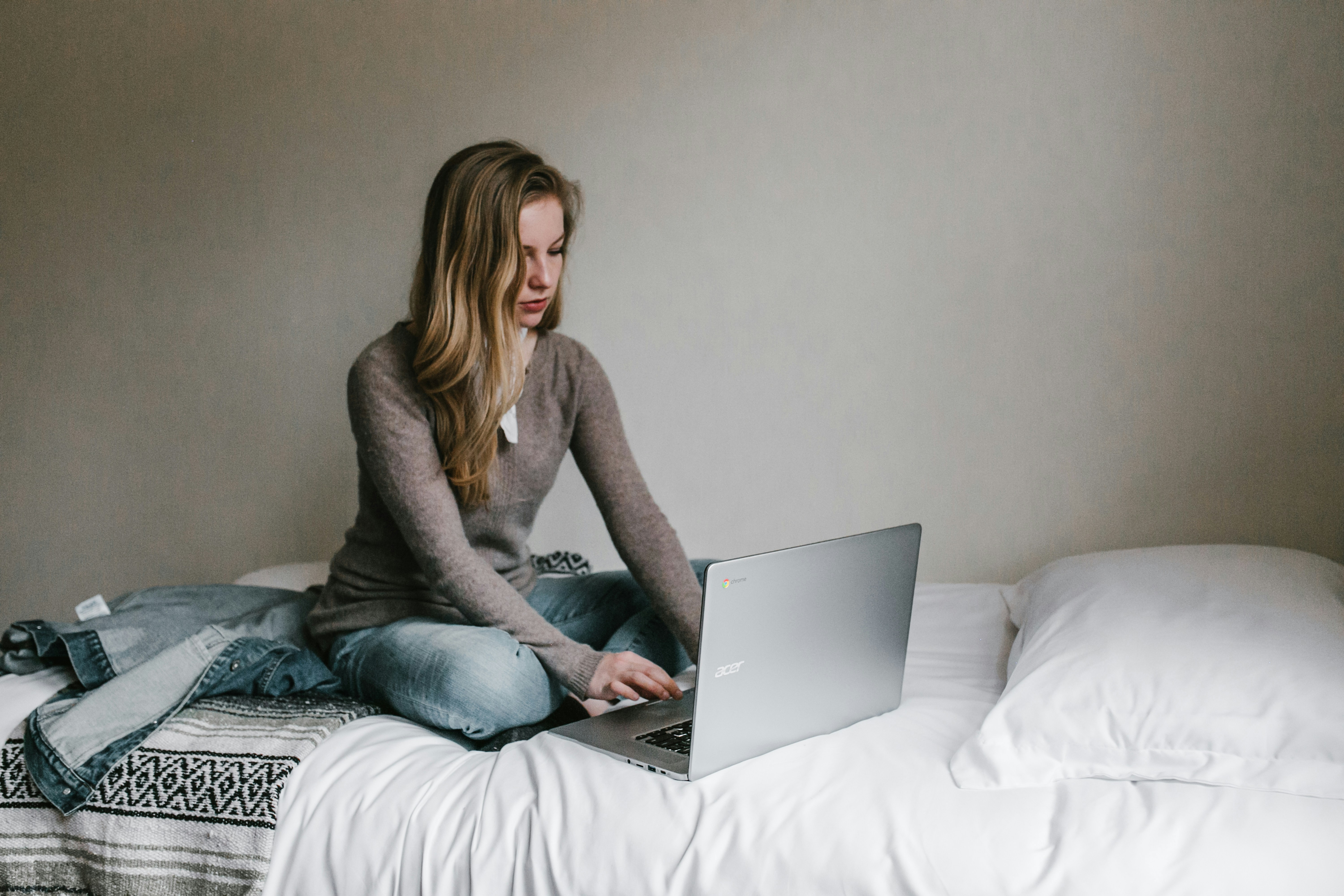 Una mujer trabajando en un portátil sentada en una cama | Fuente: Unsplash