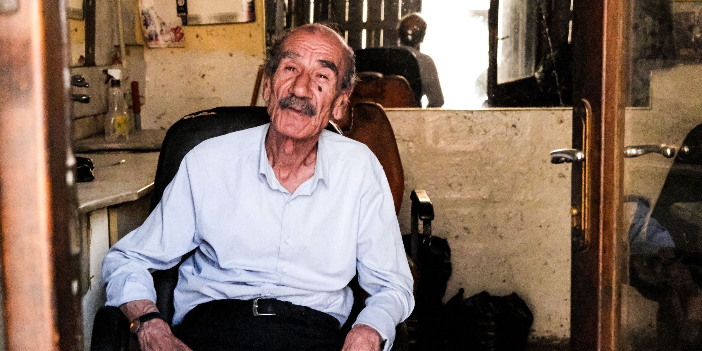Un anciano feliz sentado en una silla en una habitación | Fuente: Pexels