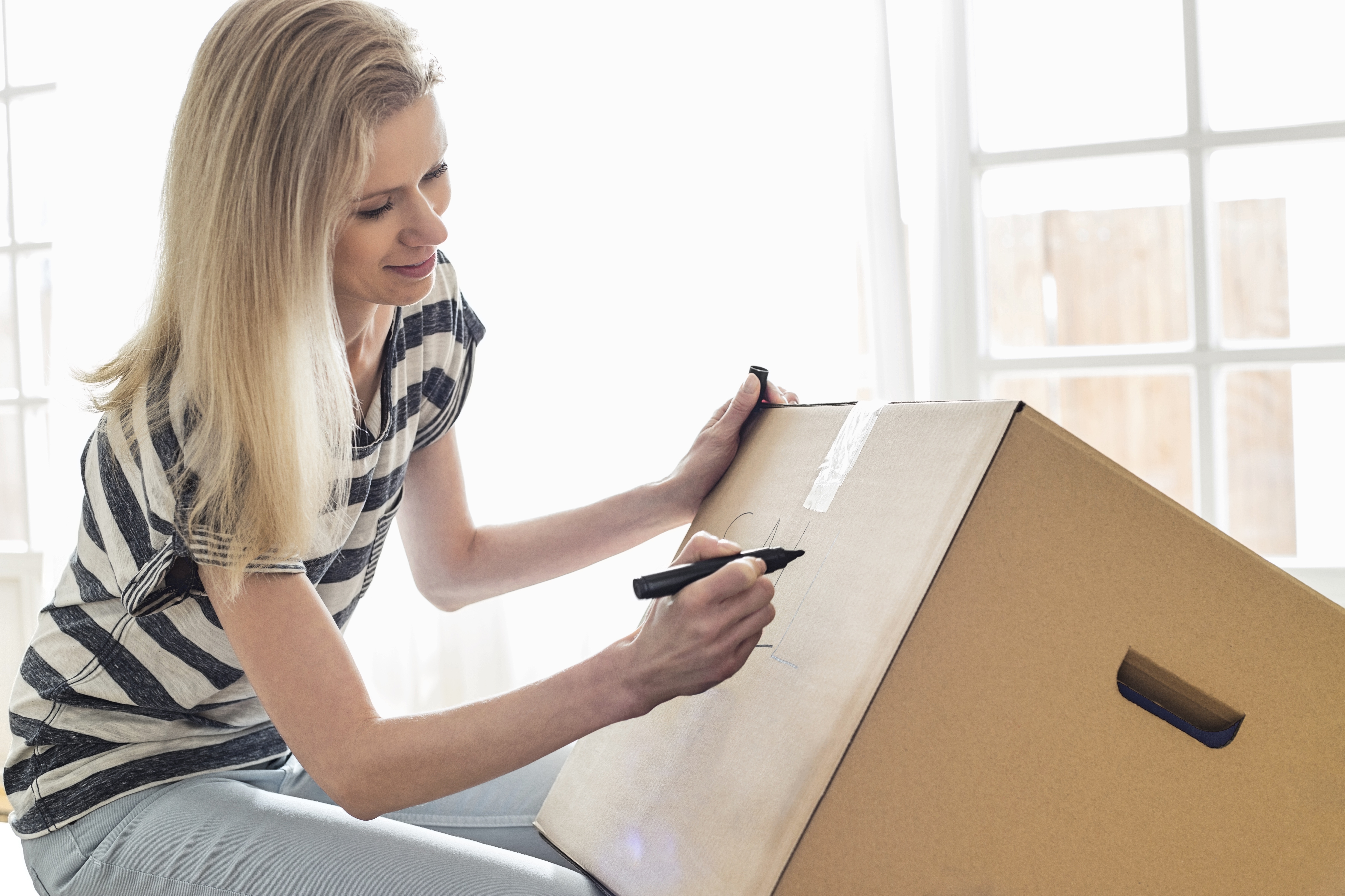 Mujer etiquetando una caja | Fuente: Shutterstock