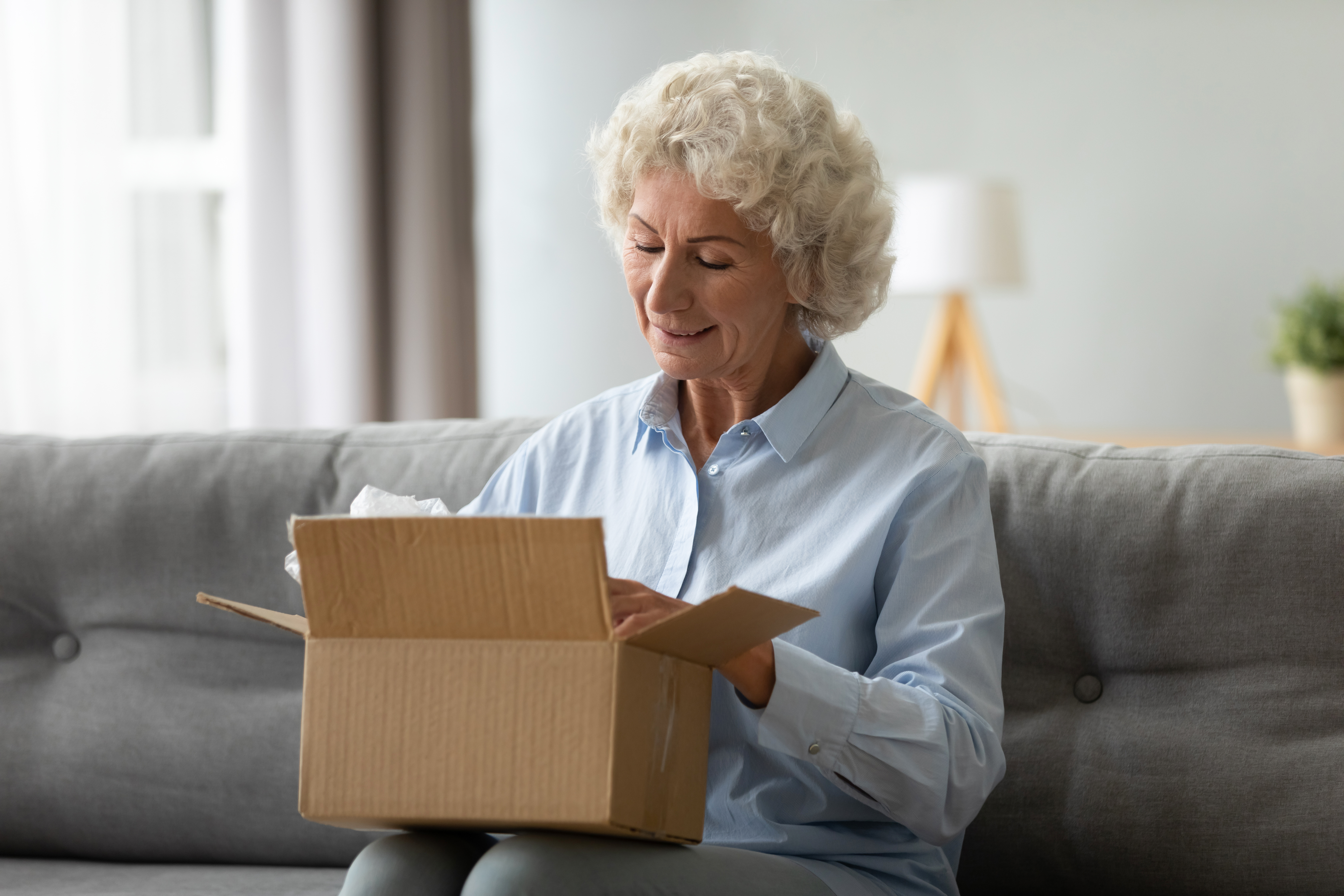 Una anciana sonriente recibe un paquete postal en su casa | Foto: Getty Images