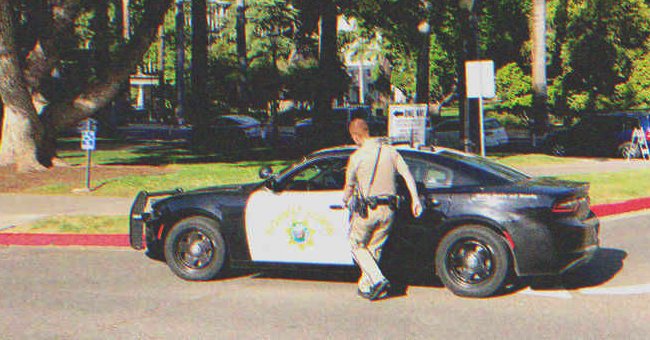 Un agente de policía entrando en un Automóvil de Policía | Fuente: Shutterstock