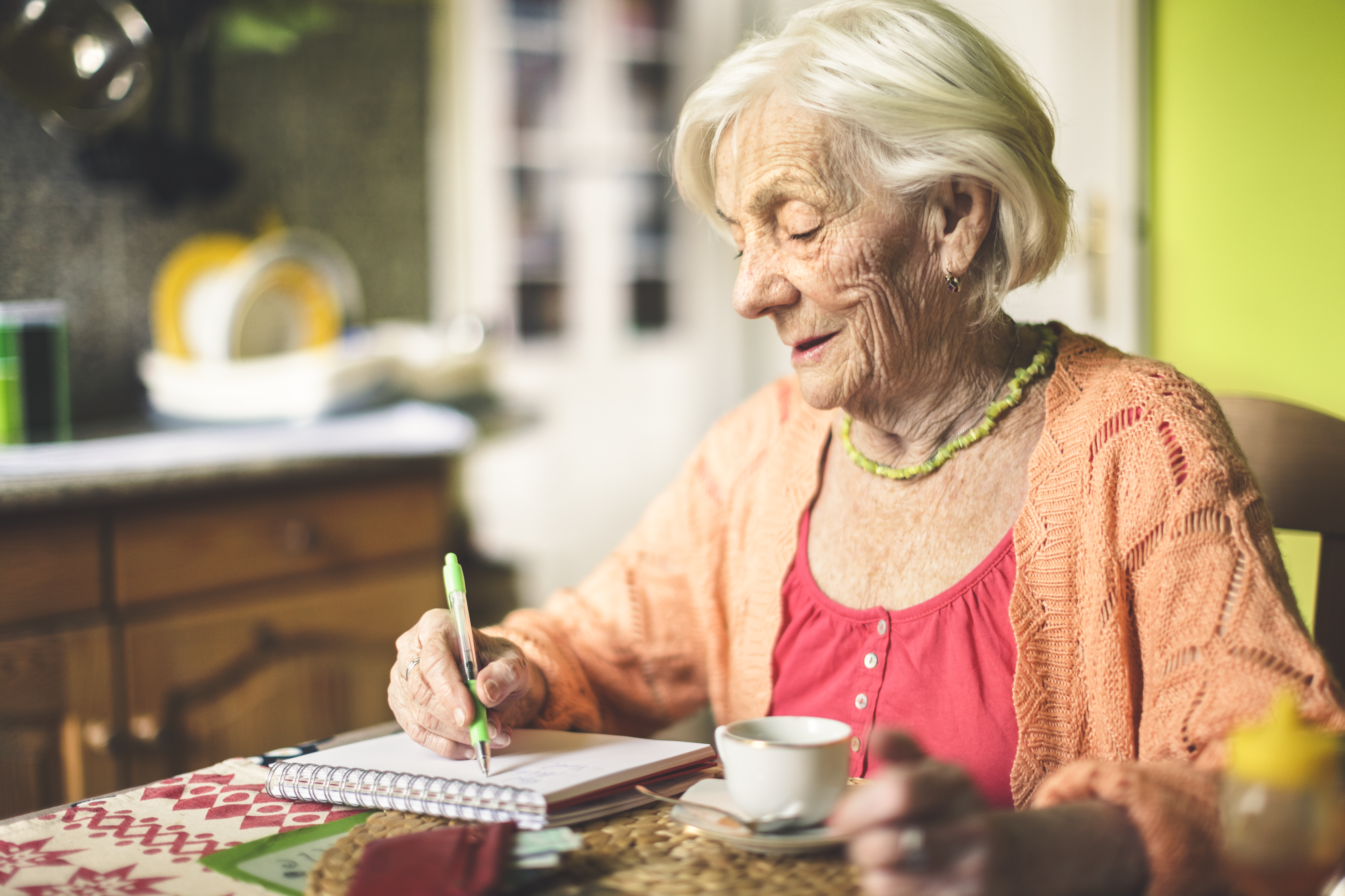 Mujer mayor haciendo anotaciones en su cocina | Foto: Getty Images